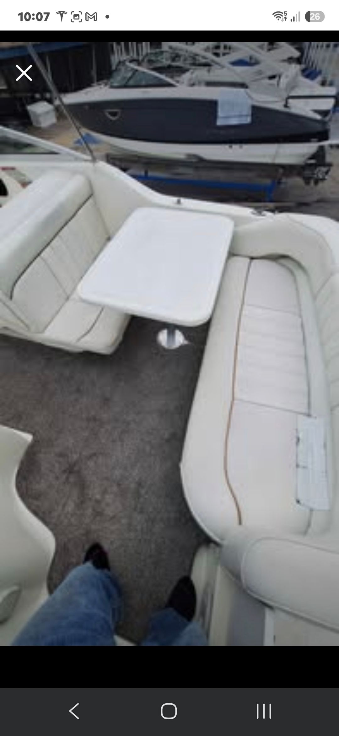 Interior of the 1998 Sea Ray 240 Sundancer with white upholstered seating and a table.