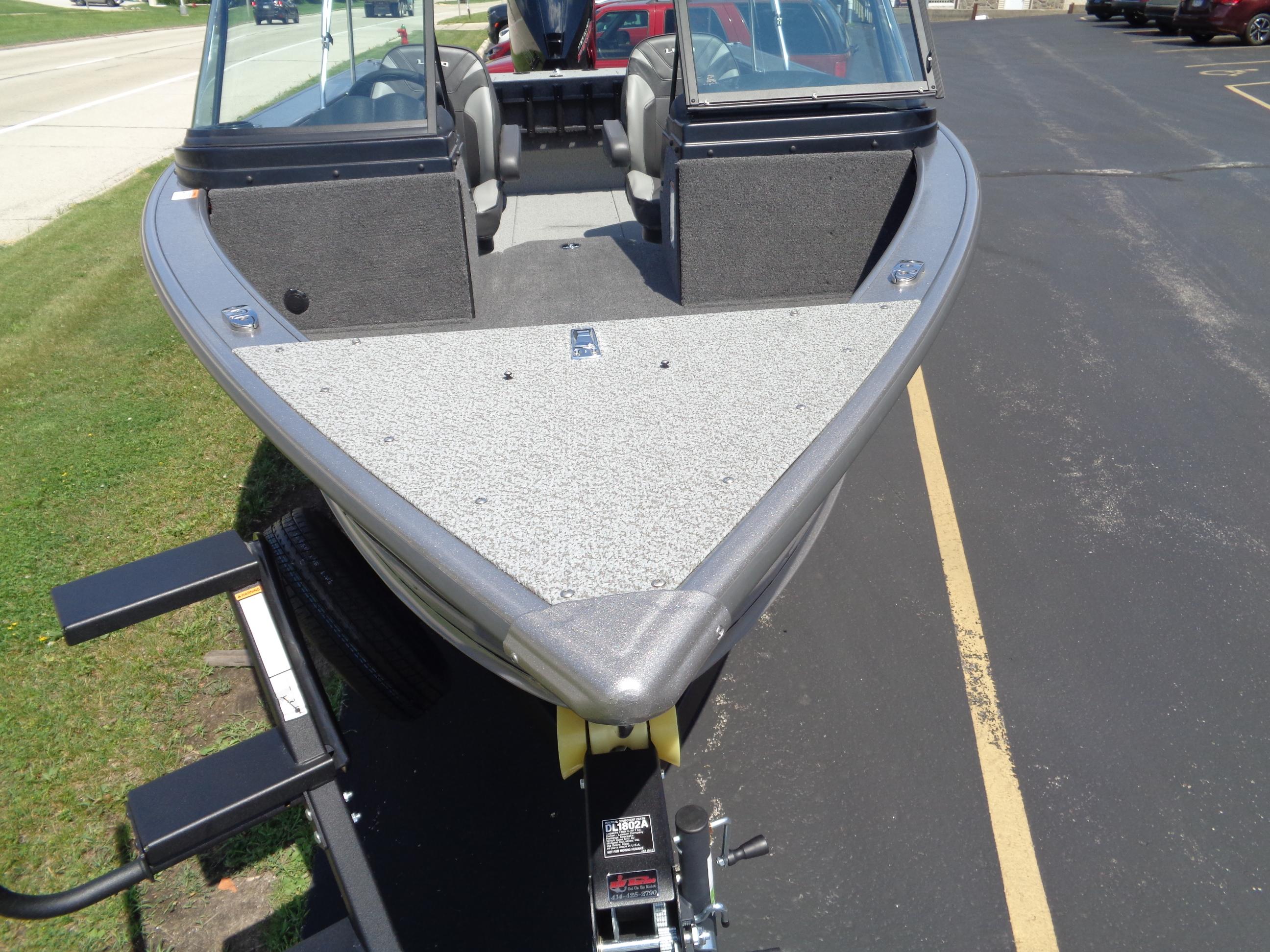 2025 Lund 2075 Fisherman boat on trailer, parked on asphalt near grass.