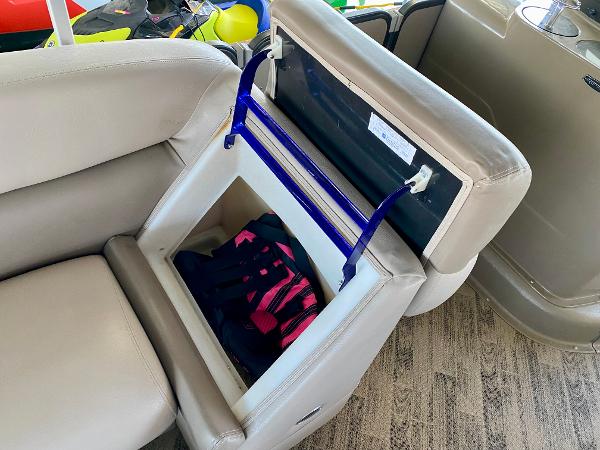 A boat seat with an open storage compartment containing a life jacket.
