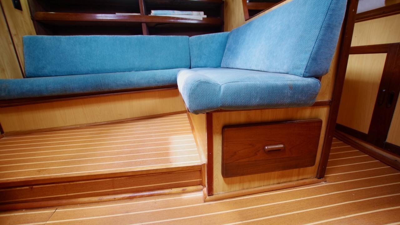 Interior of 1981 Morgan Out Island 41 yacht with blue seating and wooden flooring.