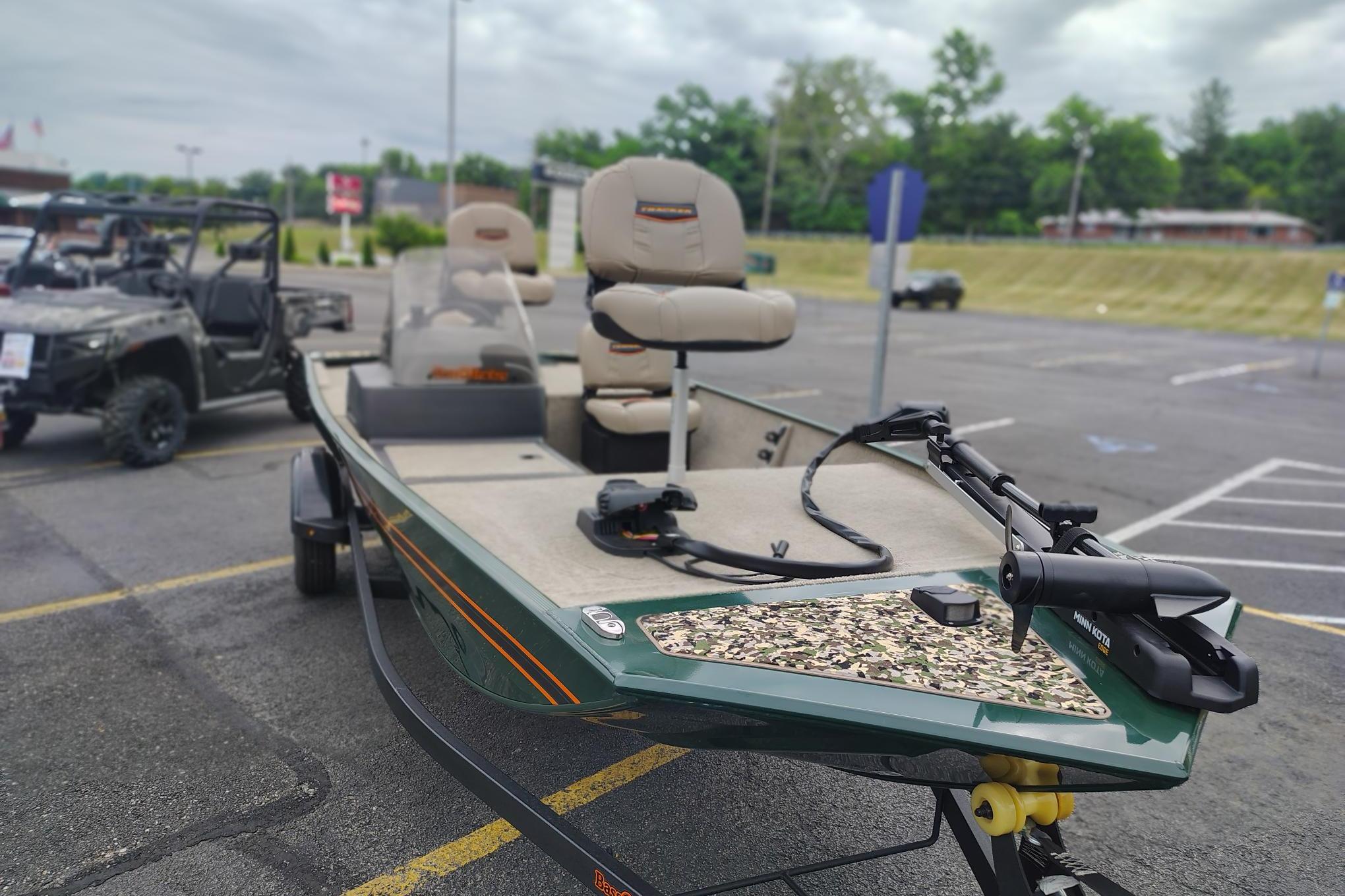 2026 Tracker Bass Tracker Classic Limited boat in parking lot, featuring beige seats and trolling motor.