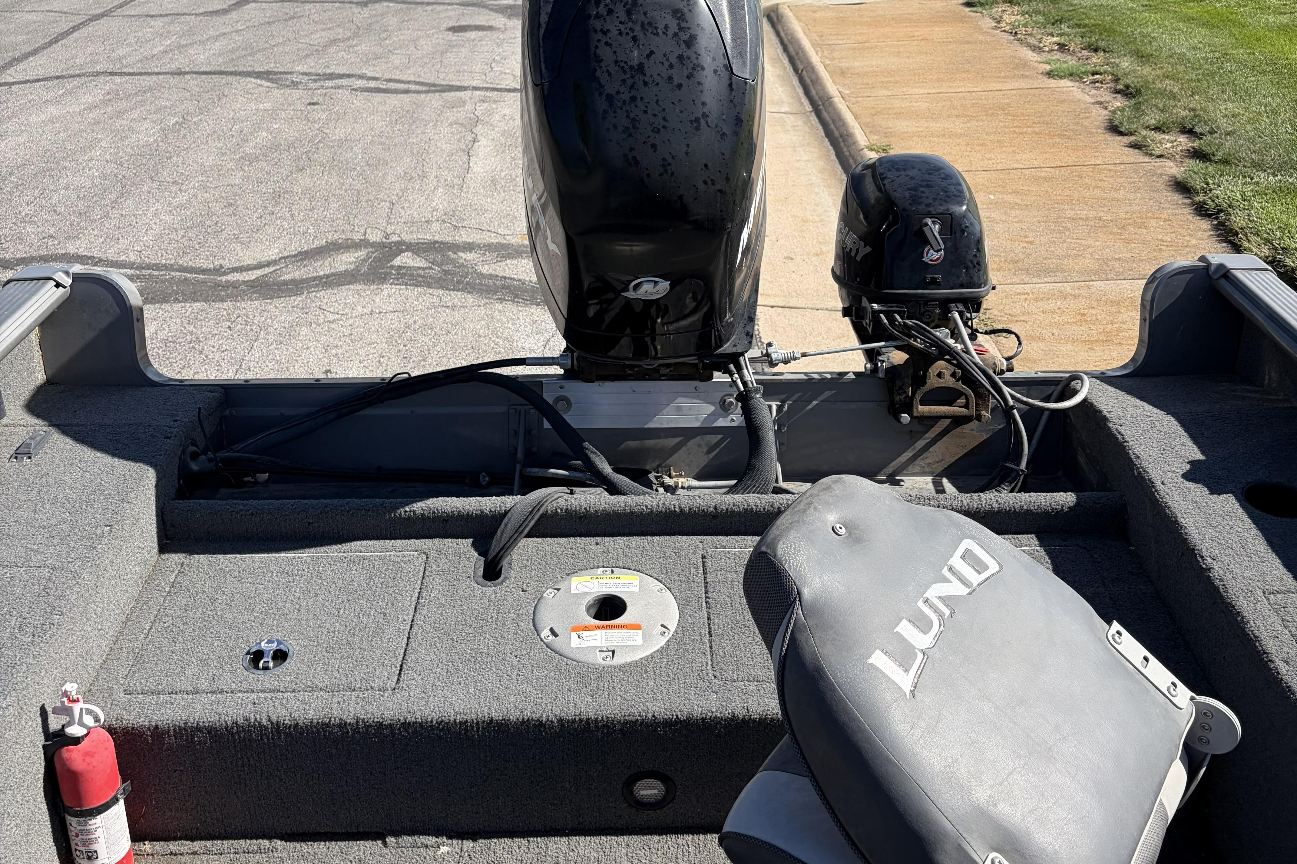 2010 Lund 1825 Explorer boat interior with motor and seating, parked on pavement.