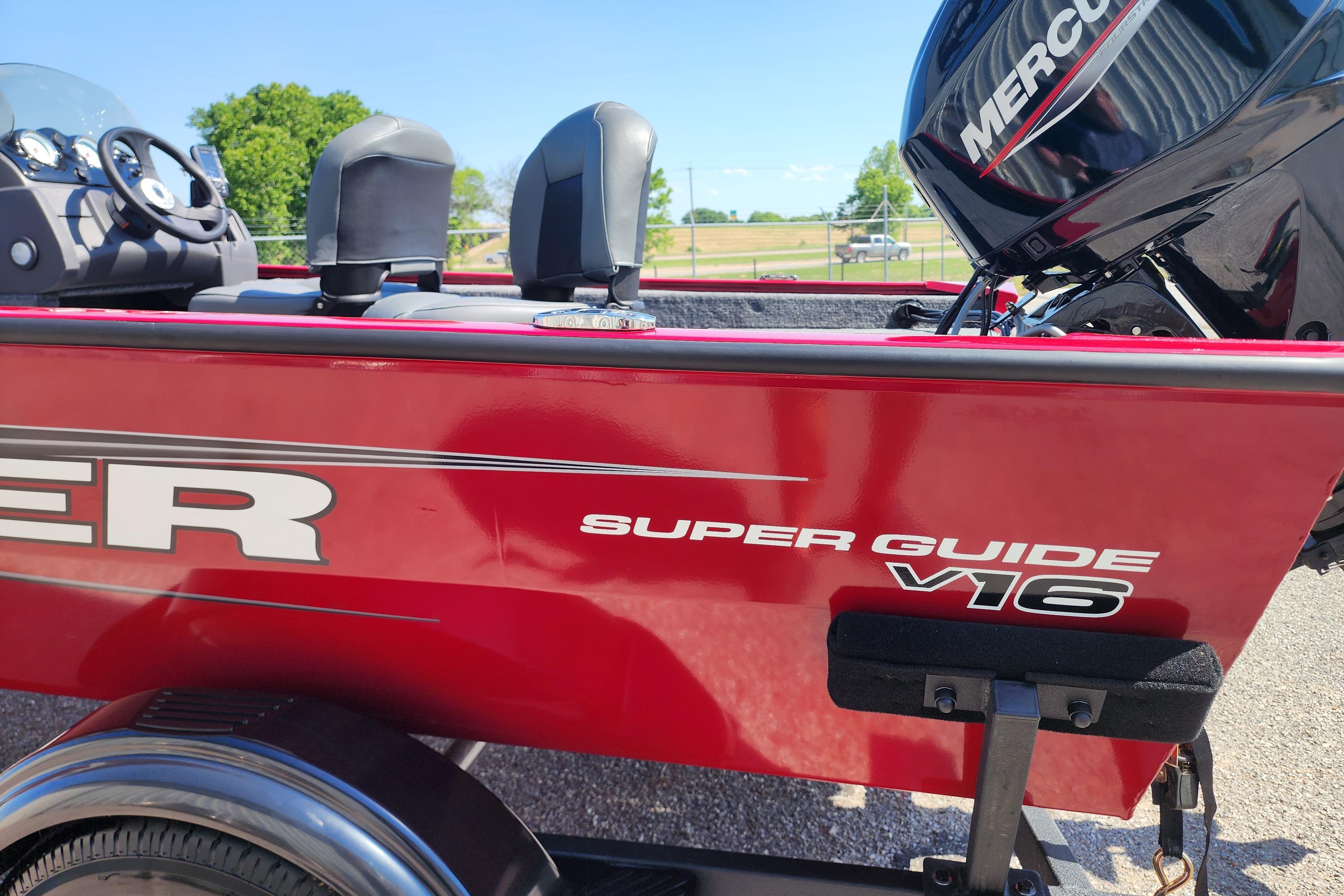 Red 2026 Tracker Super Guide V-16 SC boat with Mercury engine, parked outdoors.