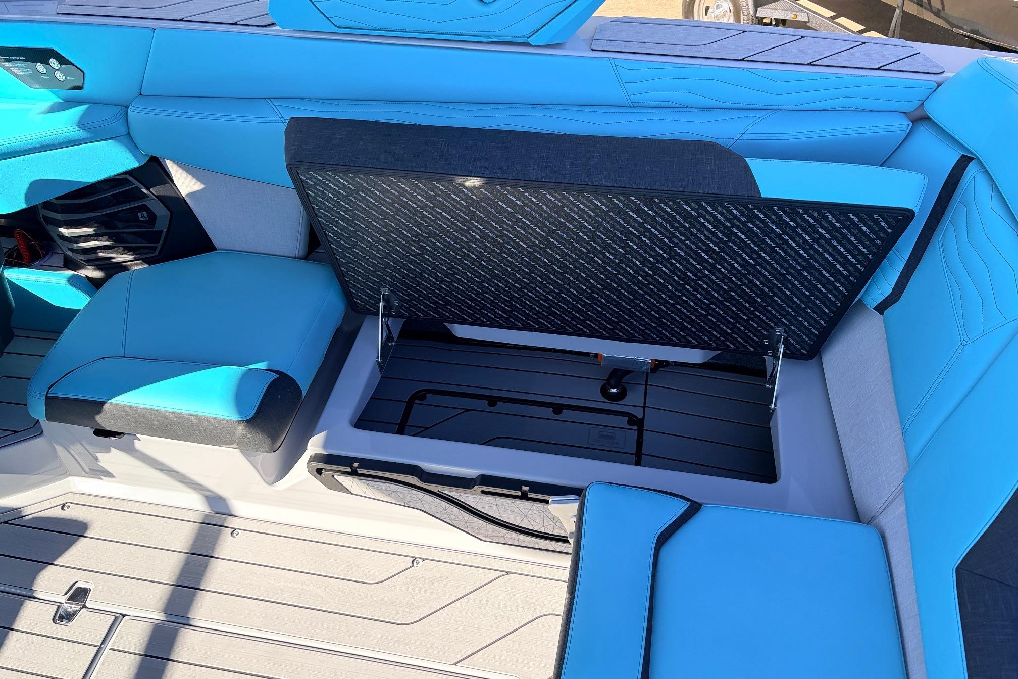 2026 Nautique Super Air Nautique G23 interior with blue seating and open storage compartment.