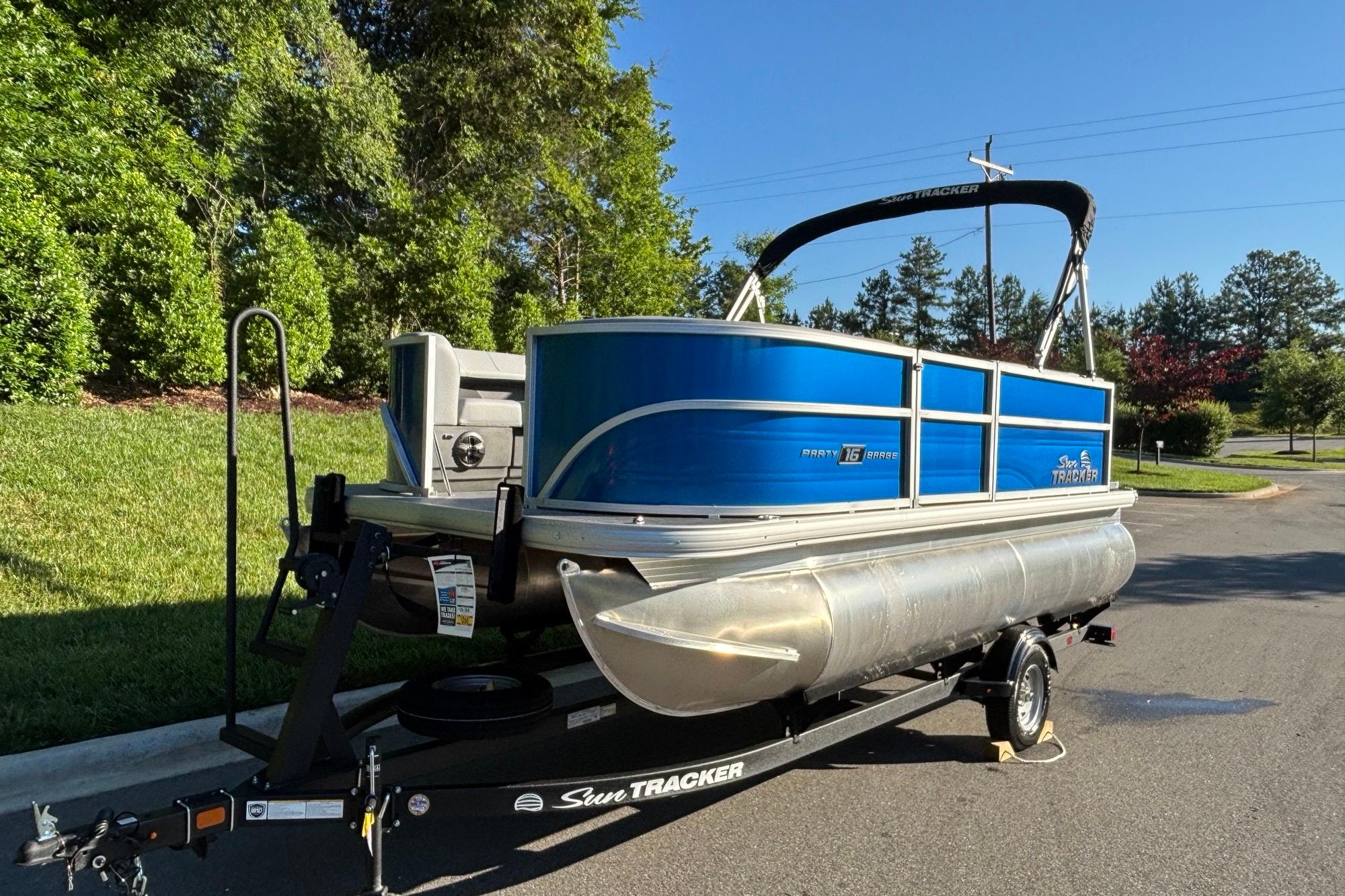 2026 Sun Tracker Party Barge 16 DLX pontoon boat on trailer, parked outdoors.