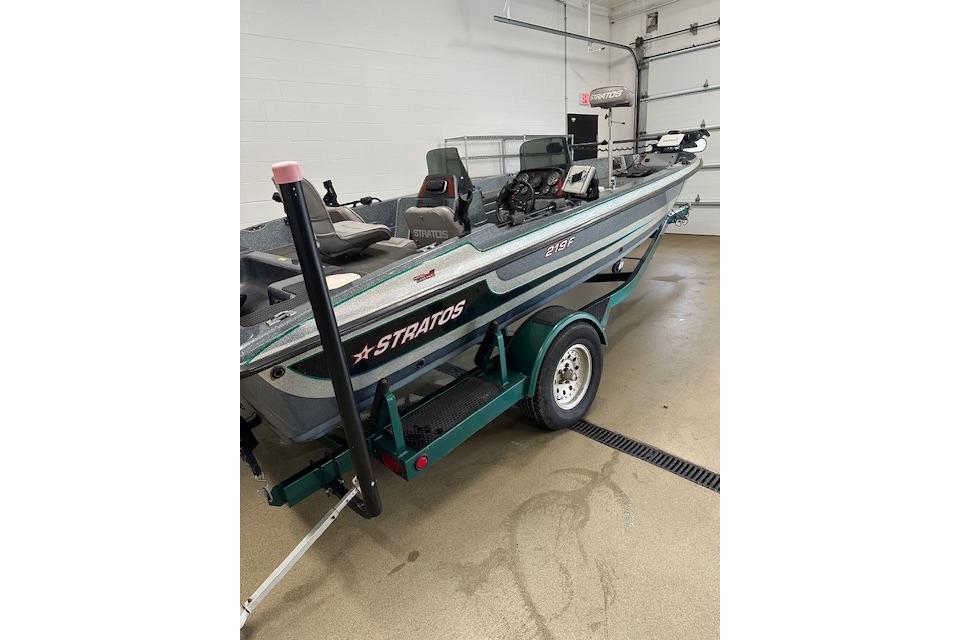 1999 Stratos 219 CF fishing boat on trailer in garage setting.