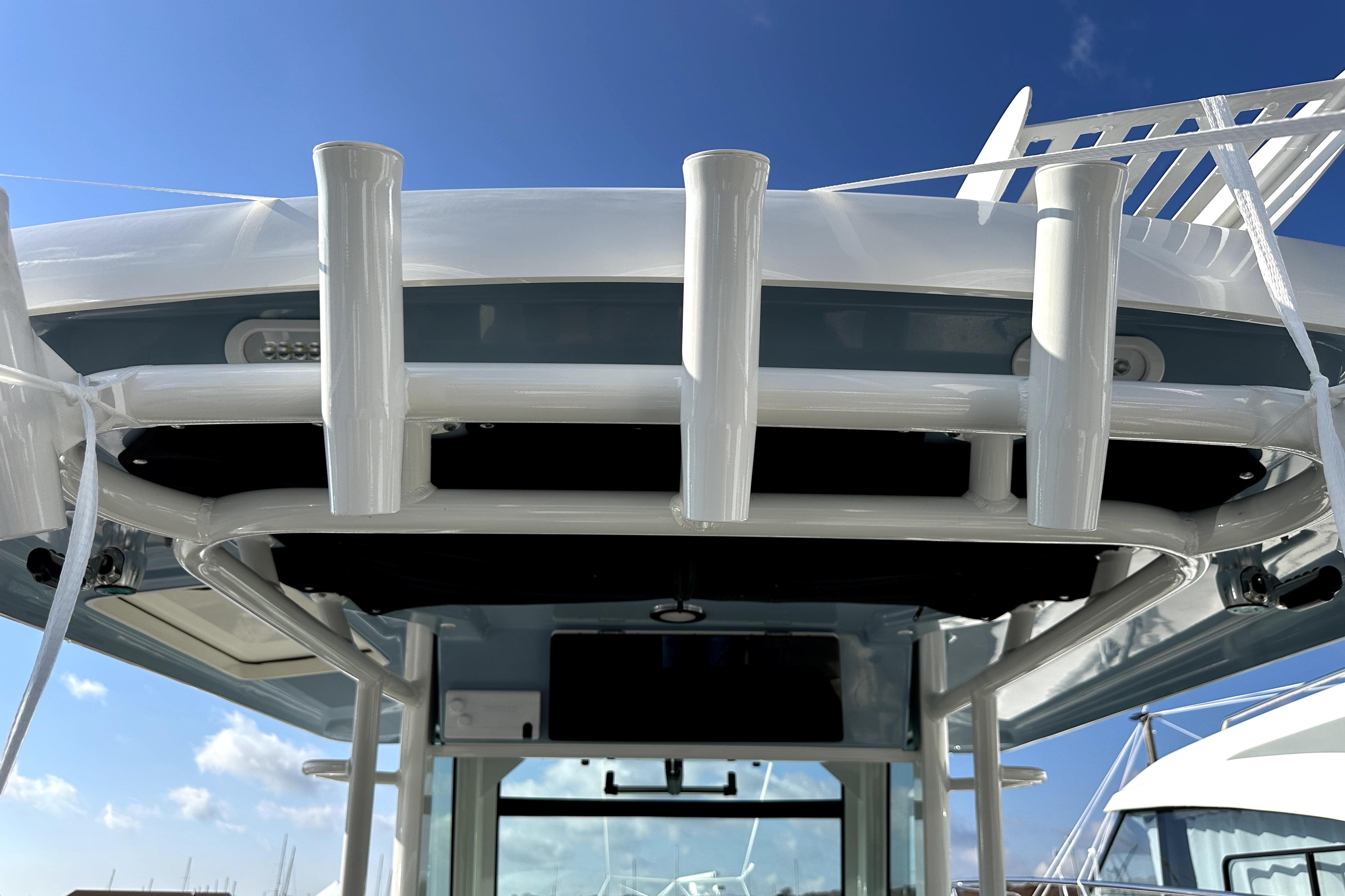 2023 Boston Whaler OUTRAGE boat with rod holders under clear blue sky.