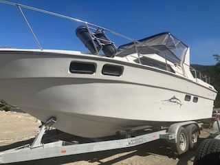 A white boat on a trailer, featuring a shark design on the side.