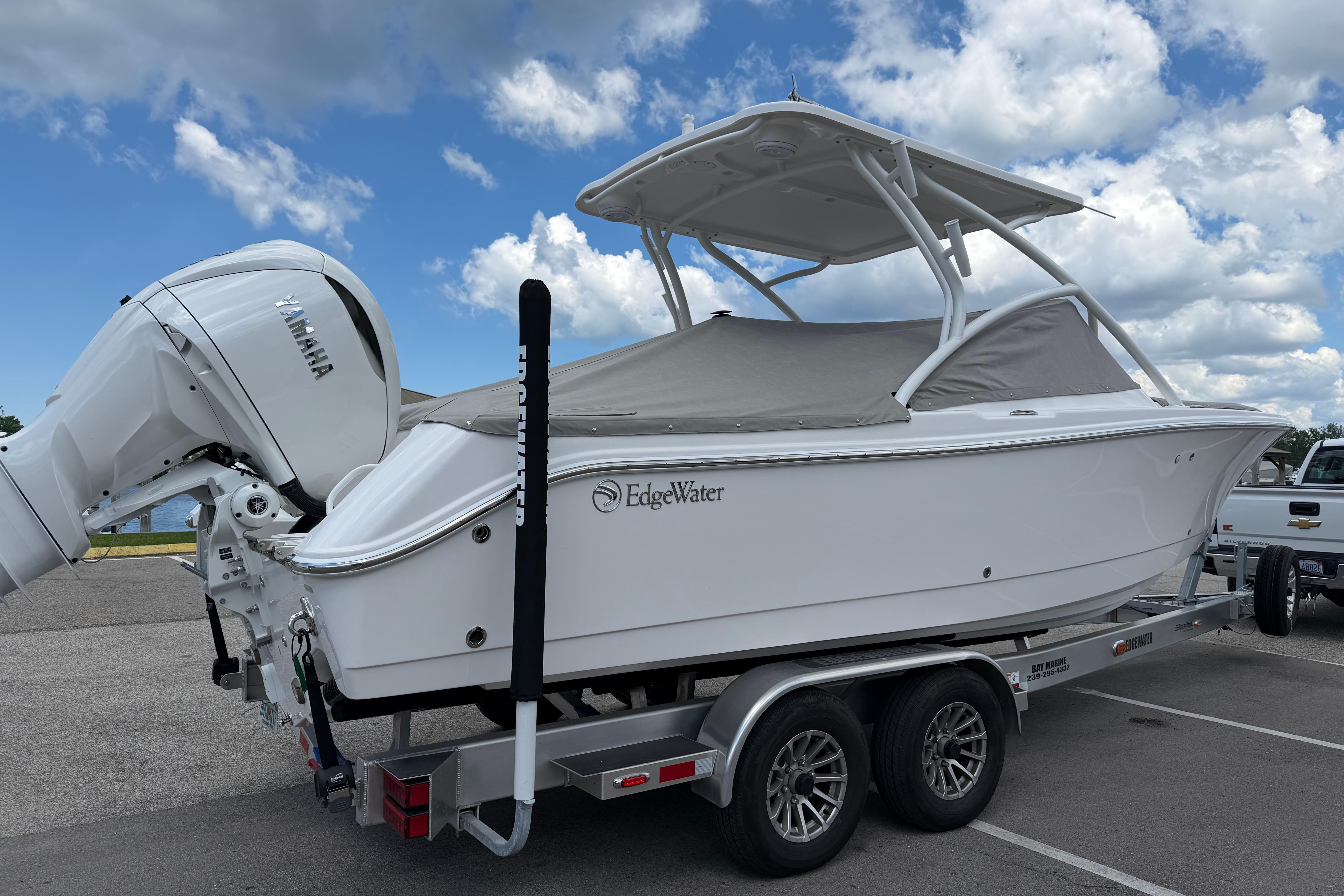 2026 Edgewater 248CX Crossover boat on trailer, covered, with Yamaha engine, under cloudy sky.