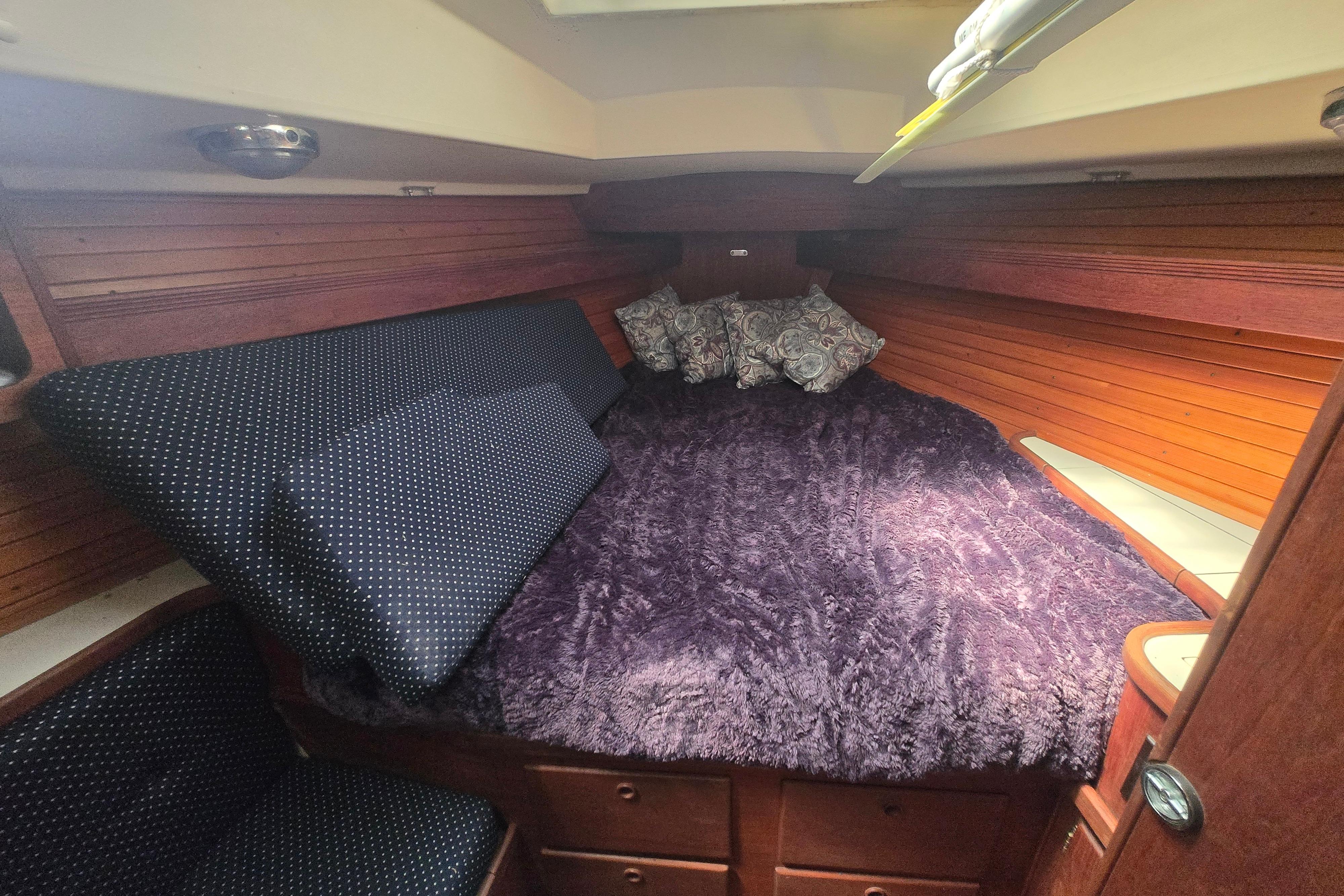 Cozy cabin interior of 1988 Sabre 38 sailboat with plush bedding and wooden paneling.