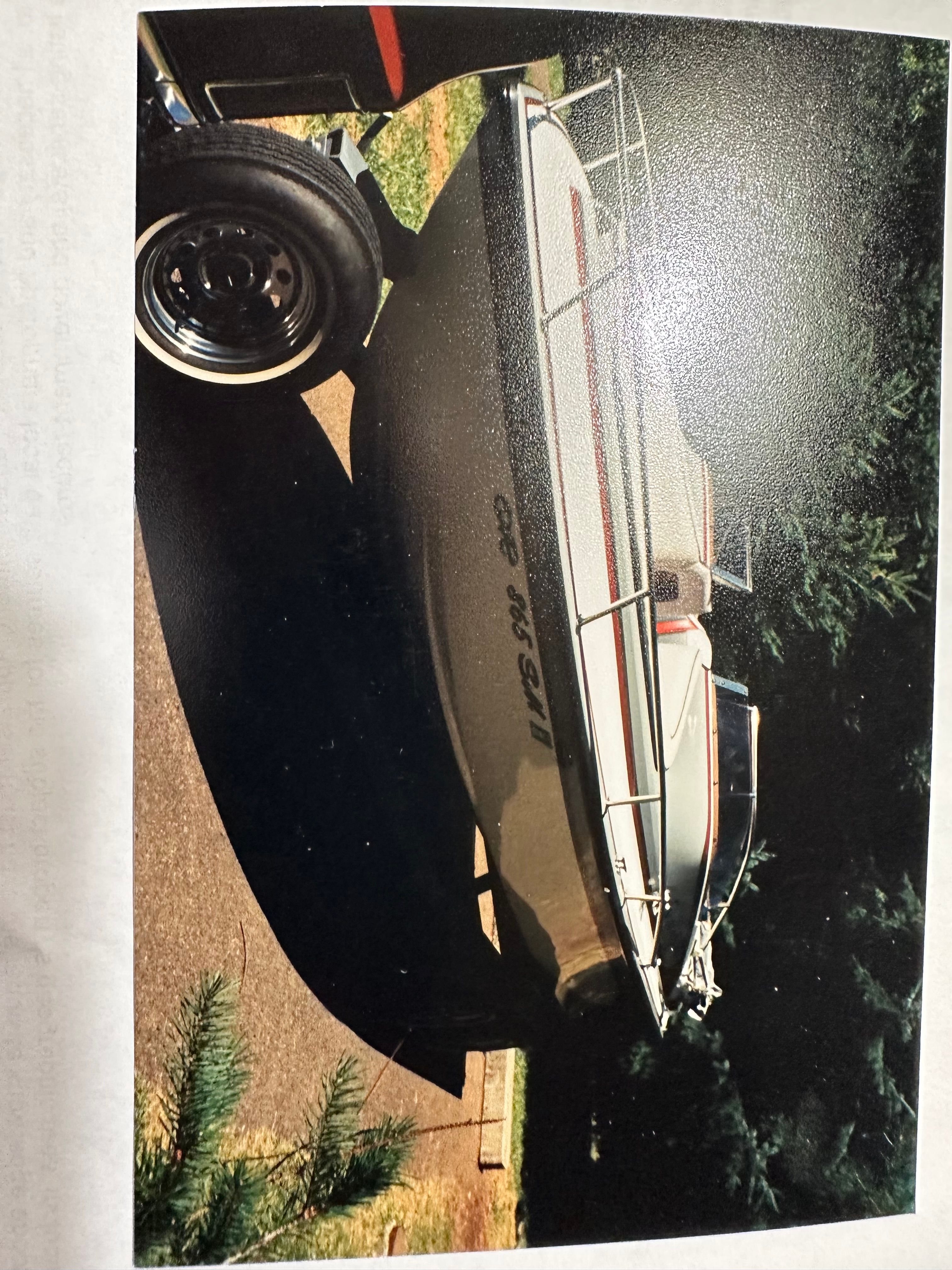 A 1990 Marlin Open Bow boat on a trailer in a wooded area.