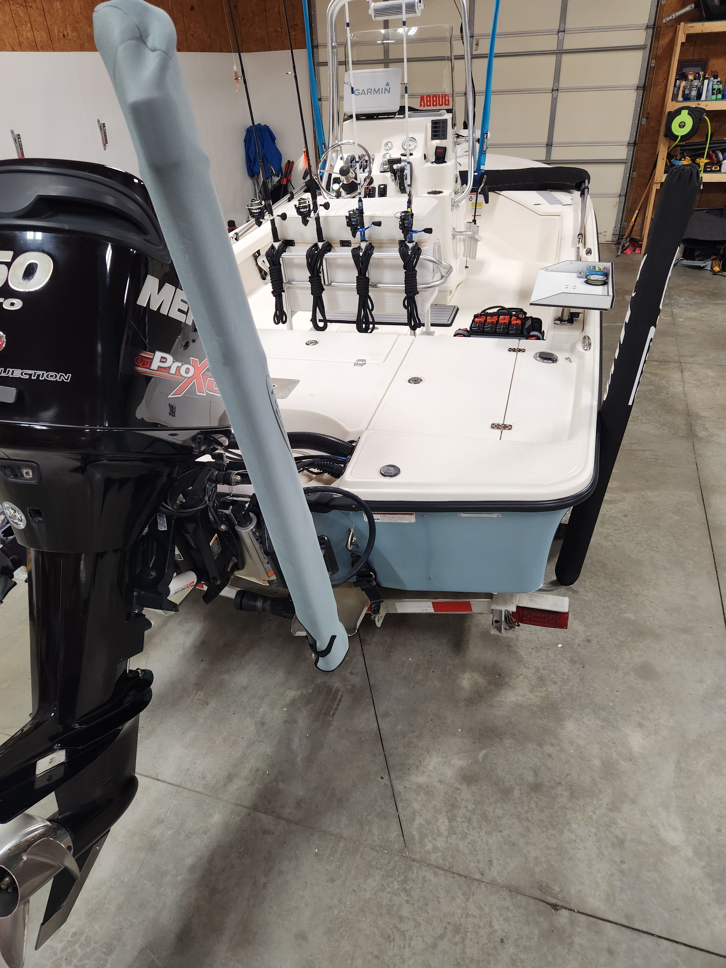 A 2014 Mako 21 LTS boat in a garage. It features a Mercury outboard motor.