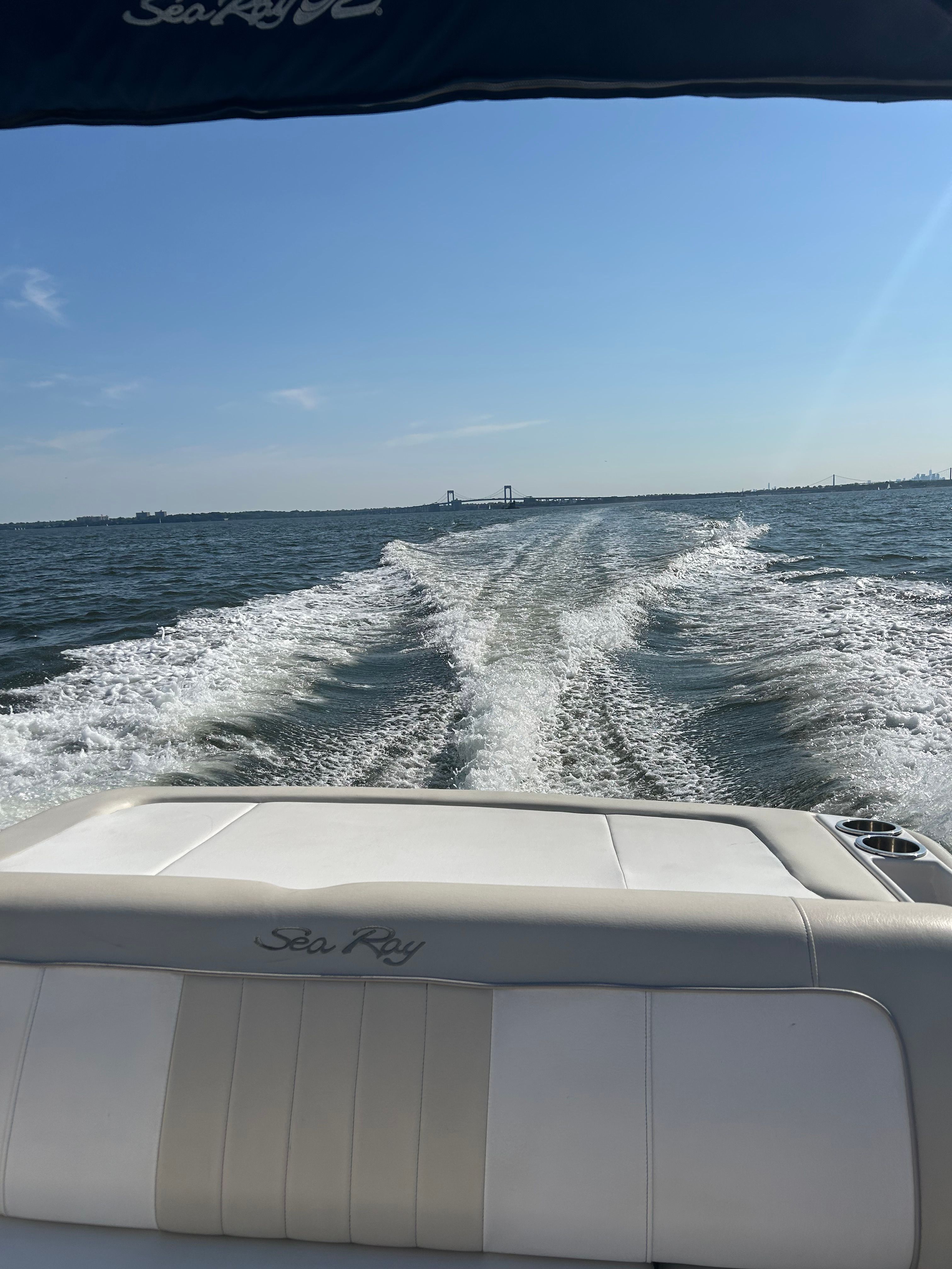 A 2013 Sea Ray 220 Sundeck cruising on open water, leaving a wake behind.