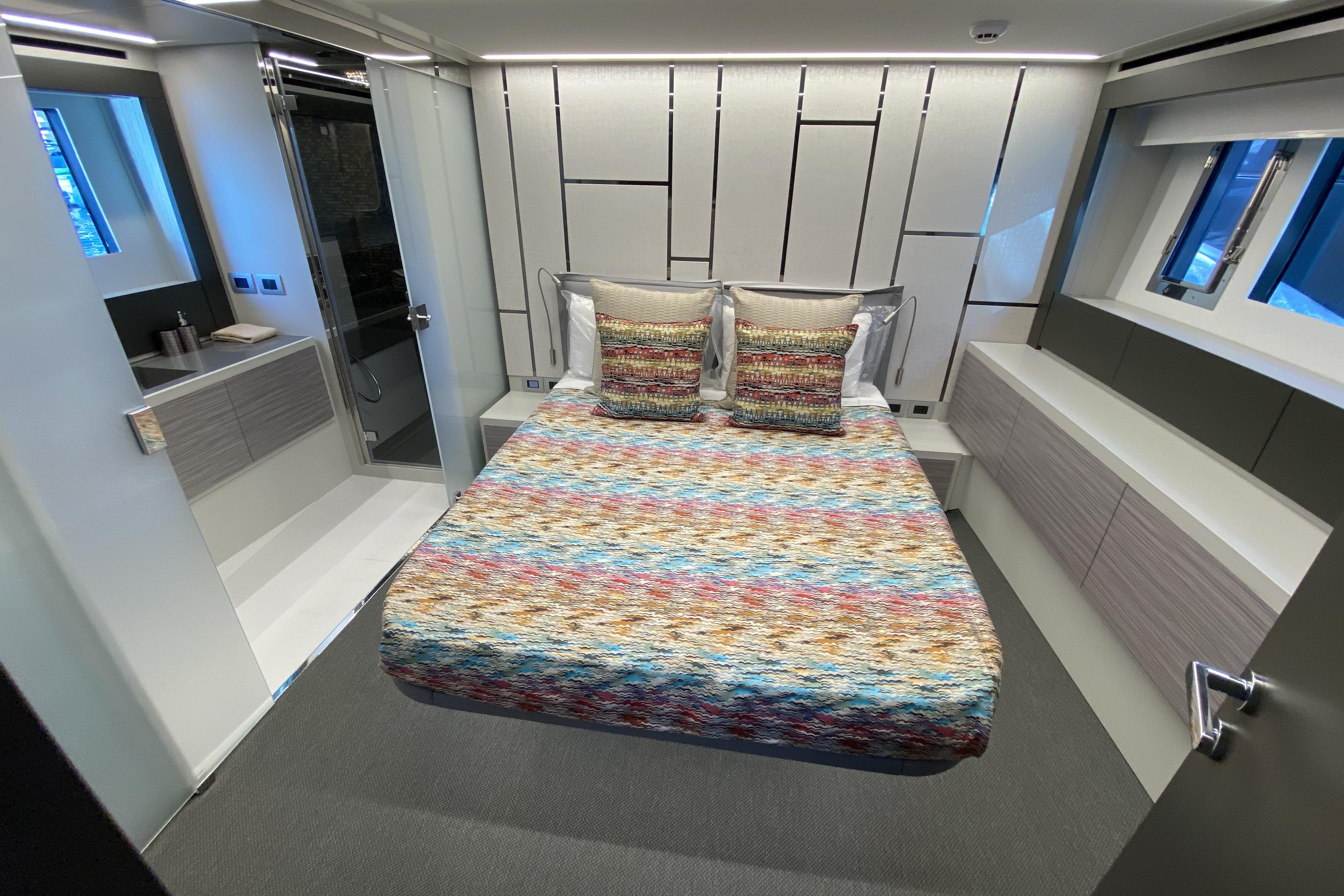 Luxurious bedroom interior of 2023 Pershing 6X yacht with modern design and colorful bedding.