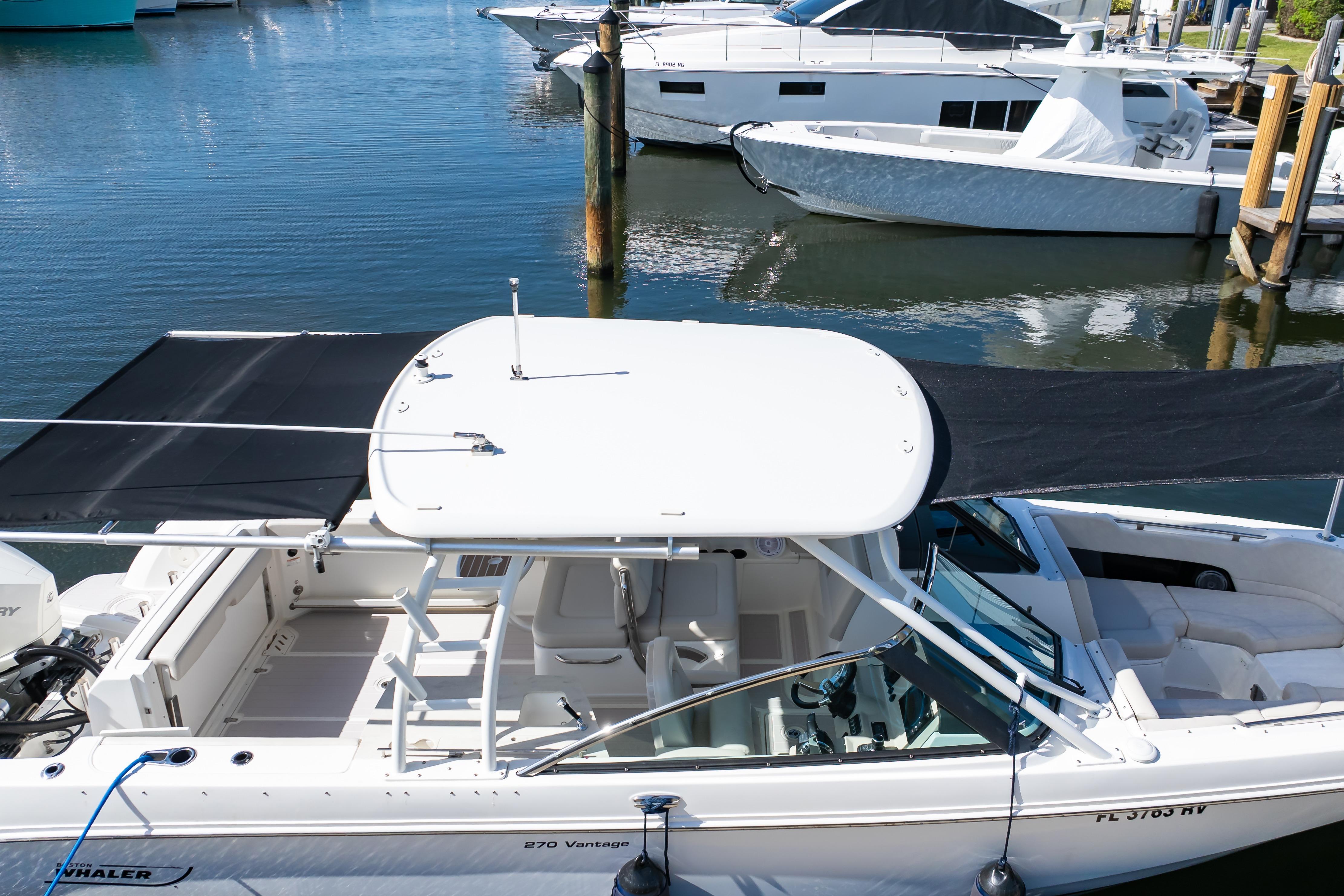 2019 Boston Whaler 270 Vantage boat docked in marina, featuring spacious seating and canopy.