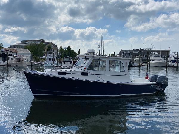 A 2015 Eastern 27 Islander boat is on the water in a harbor.