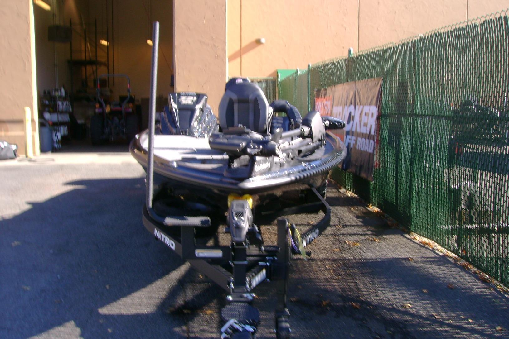 2026 Nitro Z21 XL Pro boat parked outside a garage, next to a green fence.