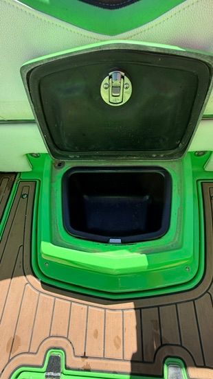 Green storage compartment lid on a boat with wooden flooring.