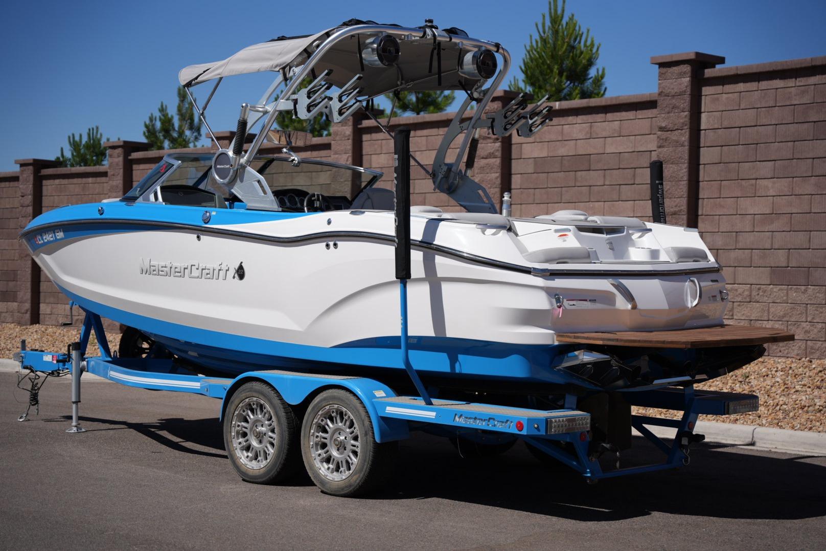 2020 MasterCraft X22 boat on trailer, blue and white design, parked outdoors.