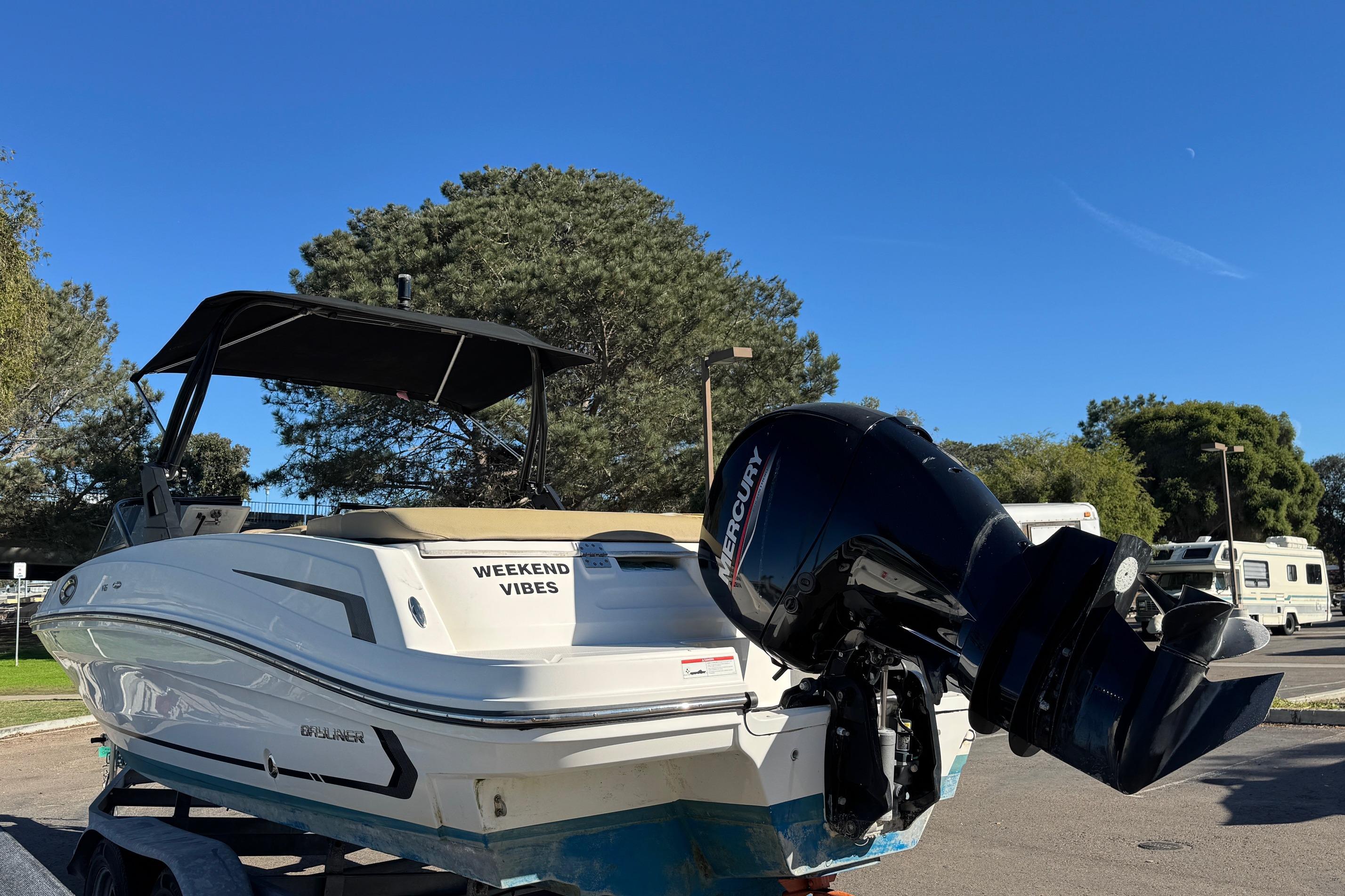 2022 Bayliner VR6 Bowrider OB with Mercury outboard motor, parked outdoors under clear blue sky.