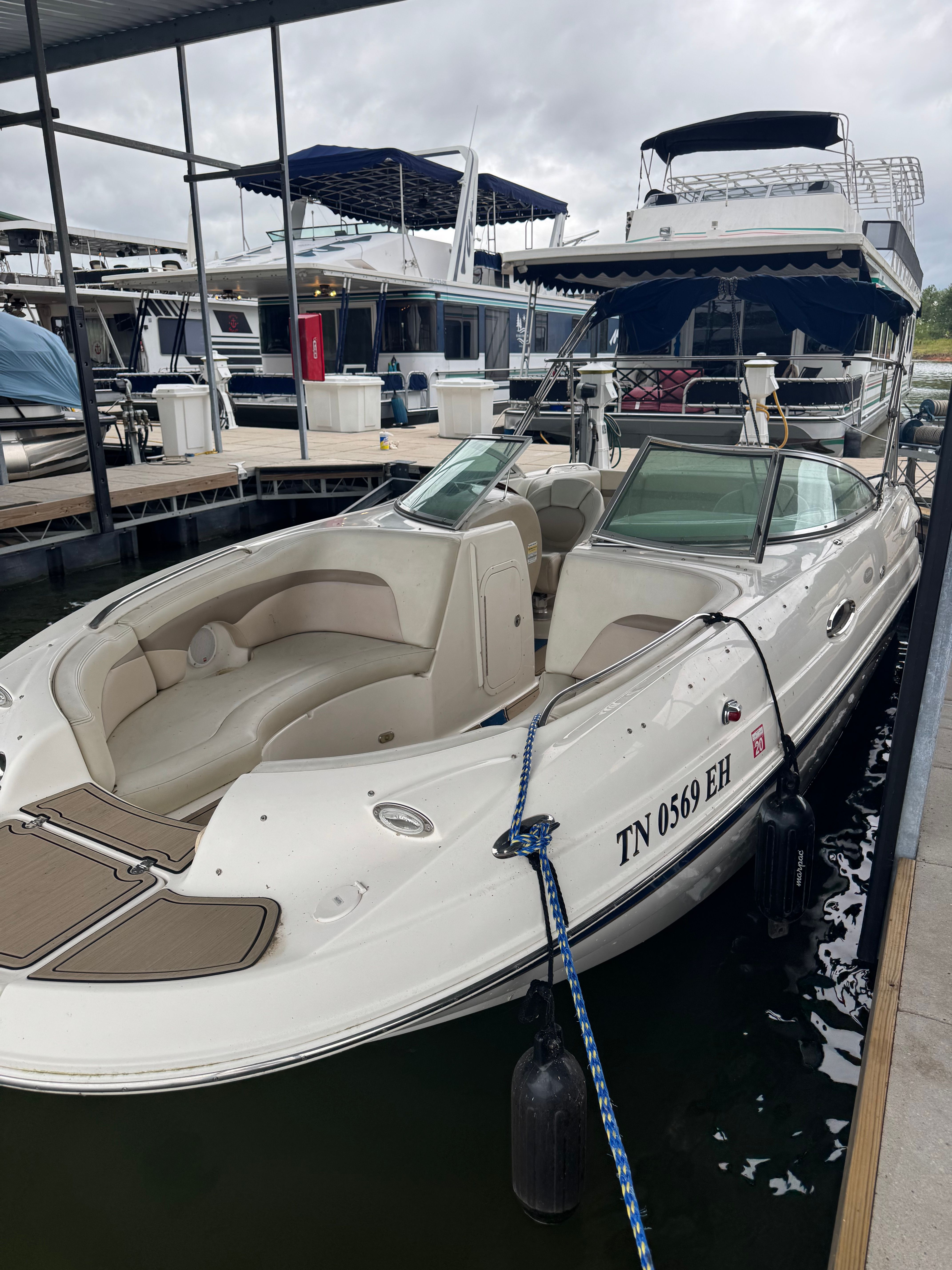 A white Chaparral Sunesta 223 boat docked in a marina, surrounded by other boats.