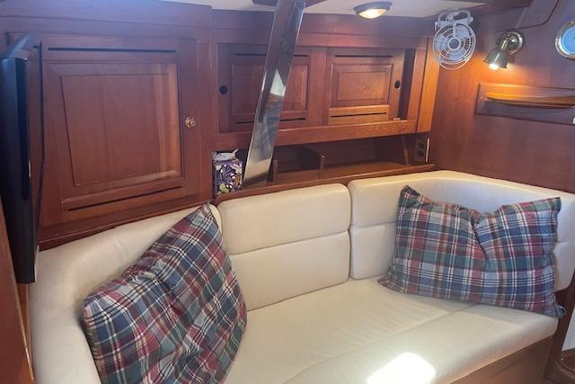 Cozy interior of 2001 Tartan 3700 sailboat with plaid pillows and wooden cabinetry.