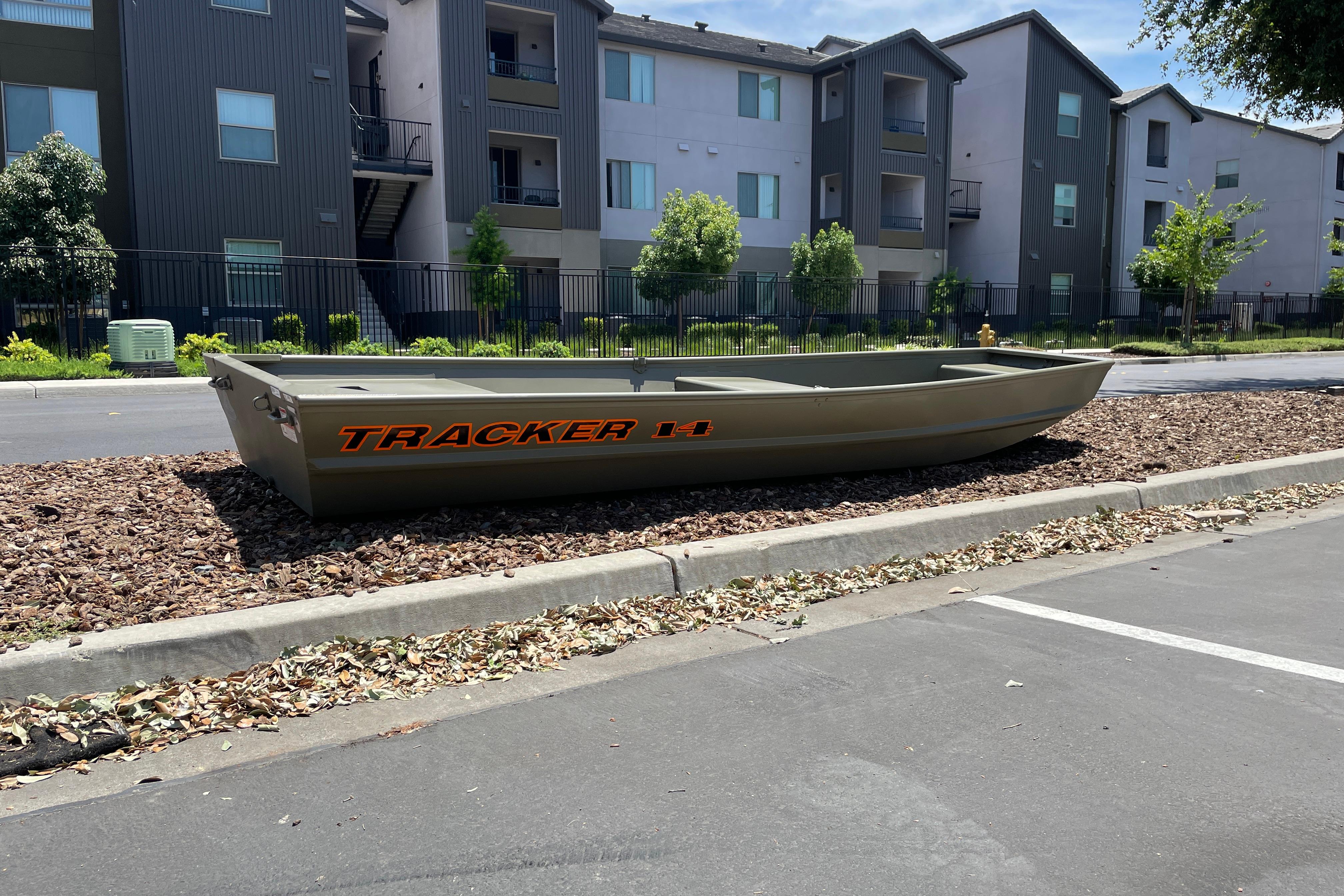 2026 Tracker Grizzly 14 Jon boat displayed outdoors near residential buildings.