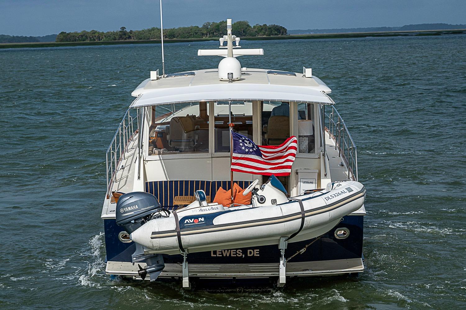 2004 Grand Banks 49 Eastbay HX yacht with American flag and dinghy on water.