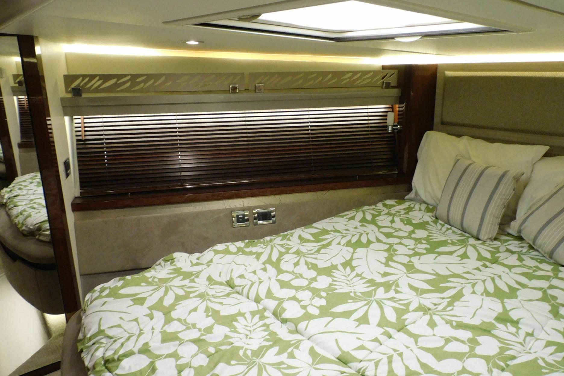 Luxurious 2019 Sea Ray L550 yacht bedroom with floral bedding and elegant wood accents.