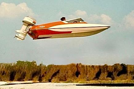 1971 Glastron/Carlson GT 15 speedboat airborne over water, showcasing vintage design and performance.