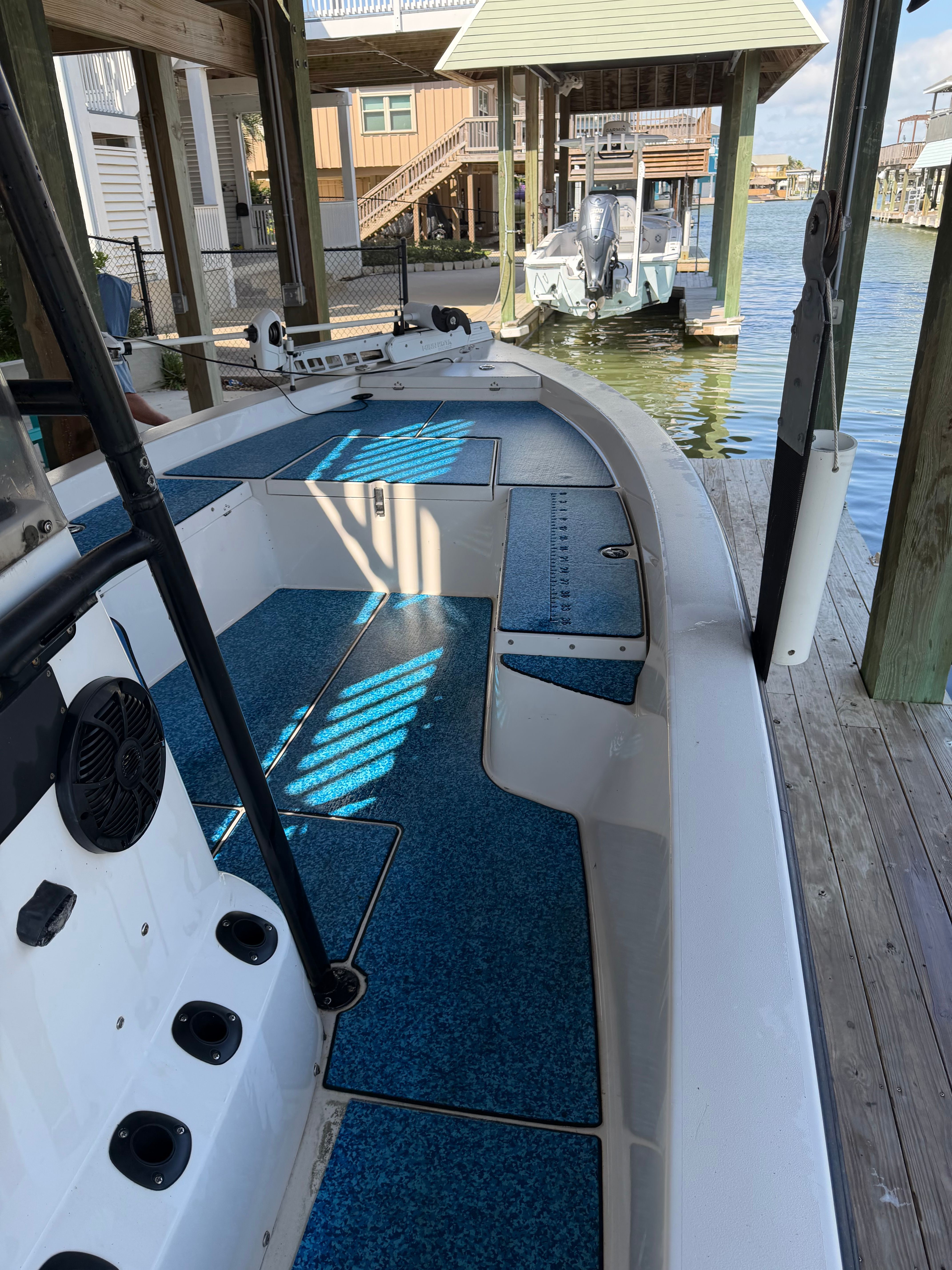 A boat with blue flooring is docked in a covered area by the water.