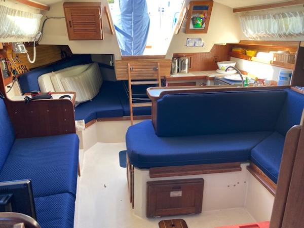 Interior of a 1989 Catalina 30 sailboat with blue seating and wooden accents.