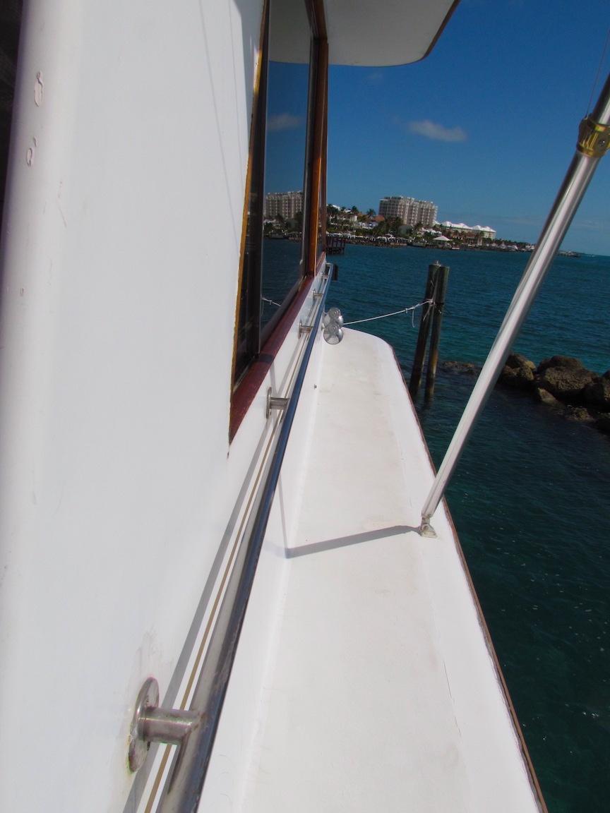 1972 Hargrave 67 Motor Yacht deck view with ocean and cityscape background.