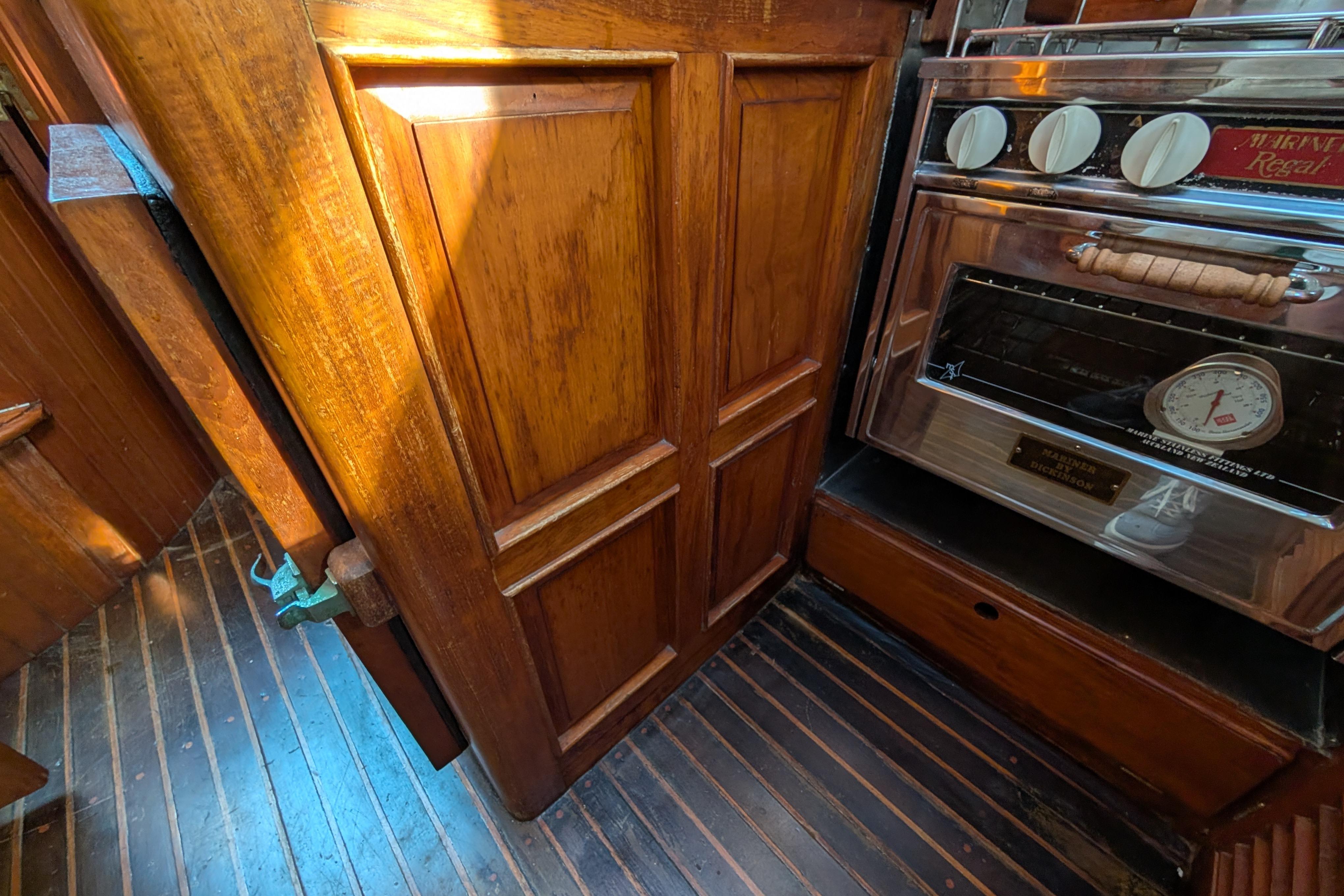 Wooden interior of 1983 Robert Perry 41 yacht with stove and cabinetry.