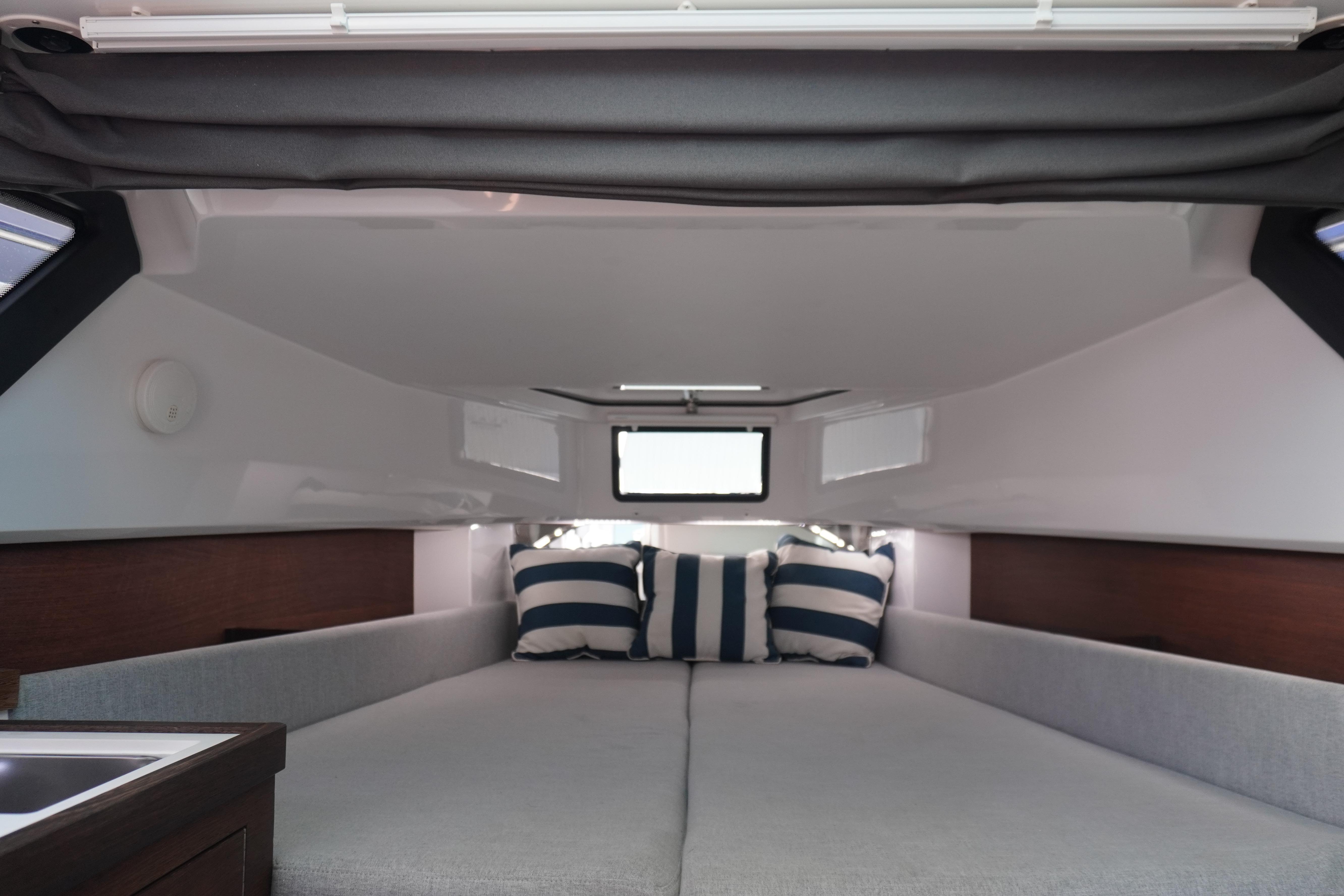 2021 Axopar 37 XC Cross Cabin interior with cozy bed and striped pillows.