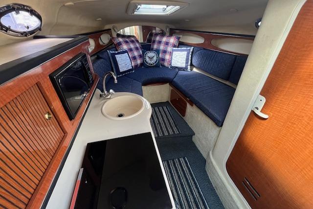 2003 Sea Ray 260 Sundancer cabin interior with kitchenette, seating, and nautical decor.