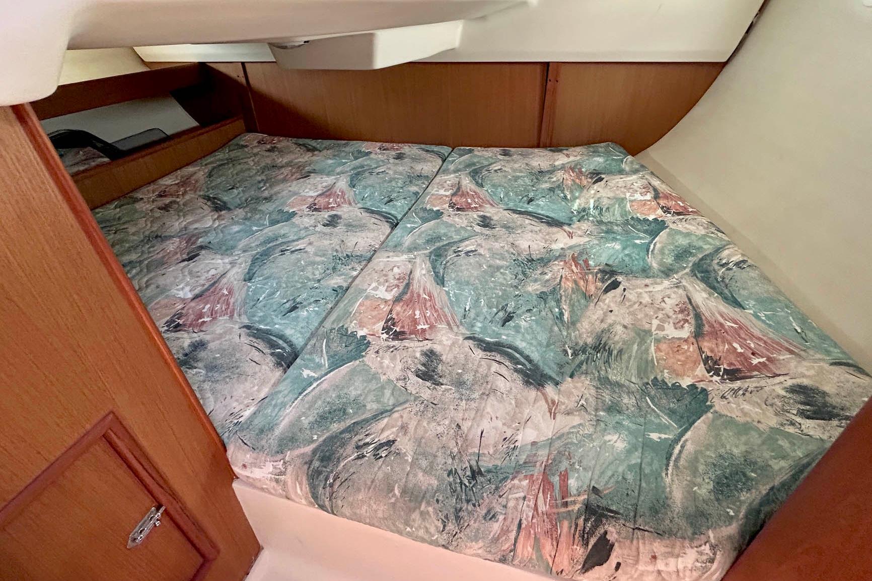 Interior cabin of a 1998 Hunter 340 sailboat with patterned bedding.
