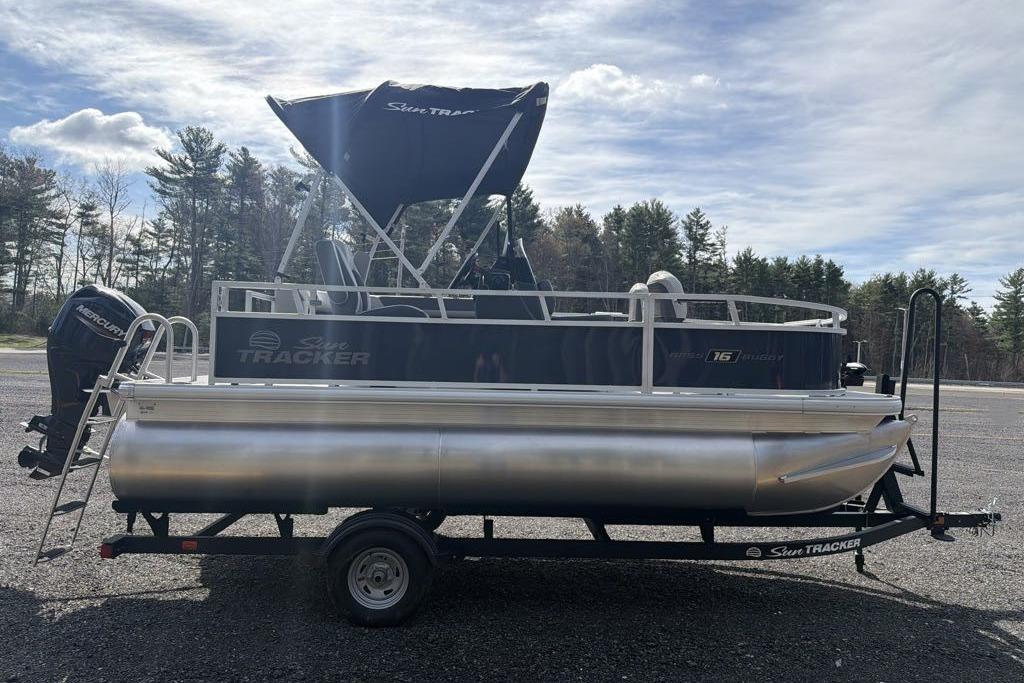 2026 Sun Tracker Bass Buggy 16 XL Select pontoon boat on trailer, outdoors.