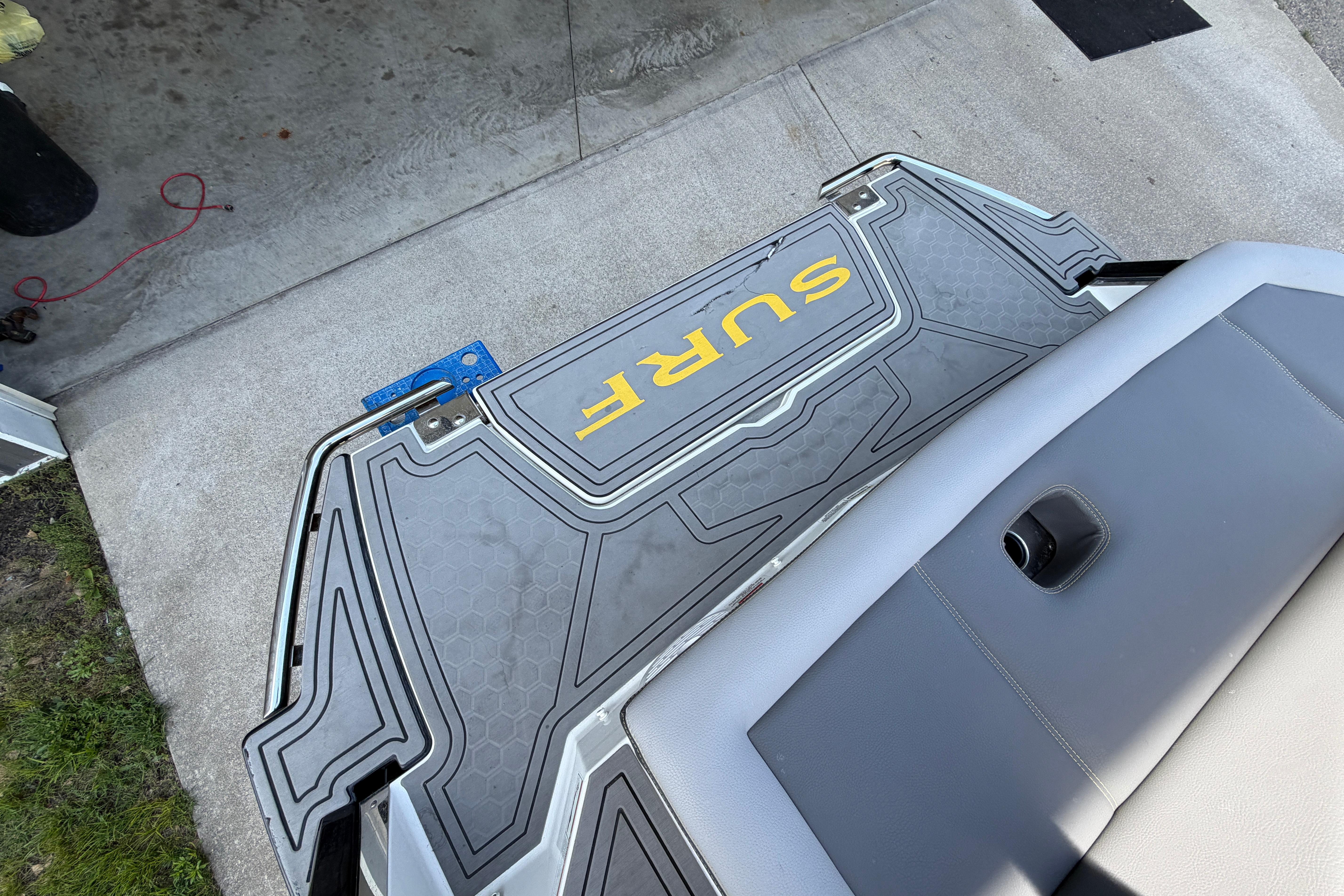 2021 Cobalt R8 Surf boat platform with "SURF" logo, gray upholstery, and concrete background.