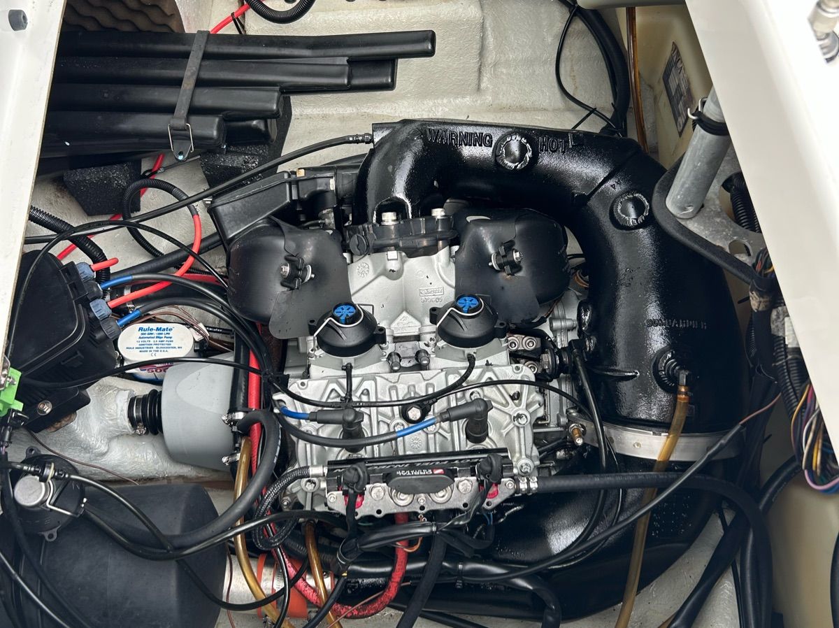 An engine compartment with a Sea-Doo engine, surrounded by wires and hoses.
