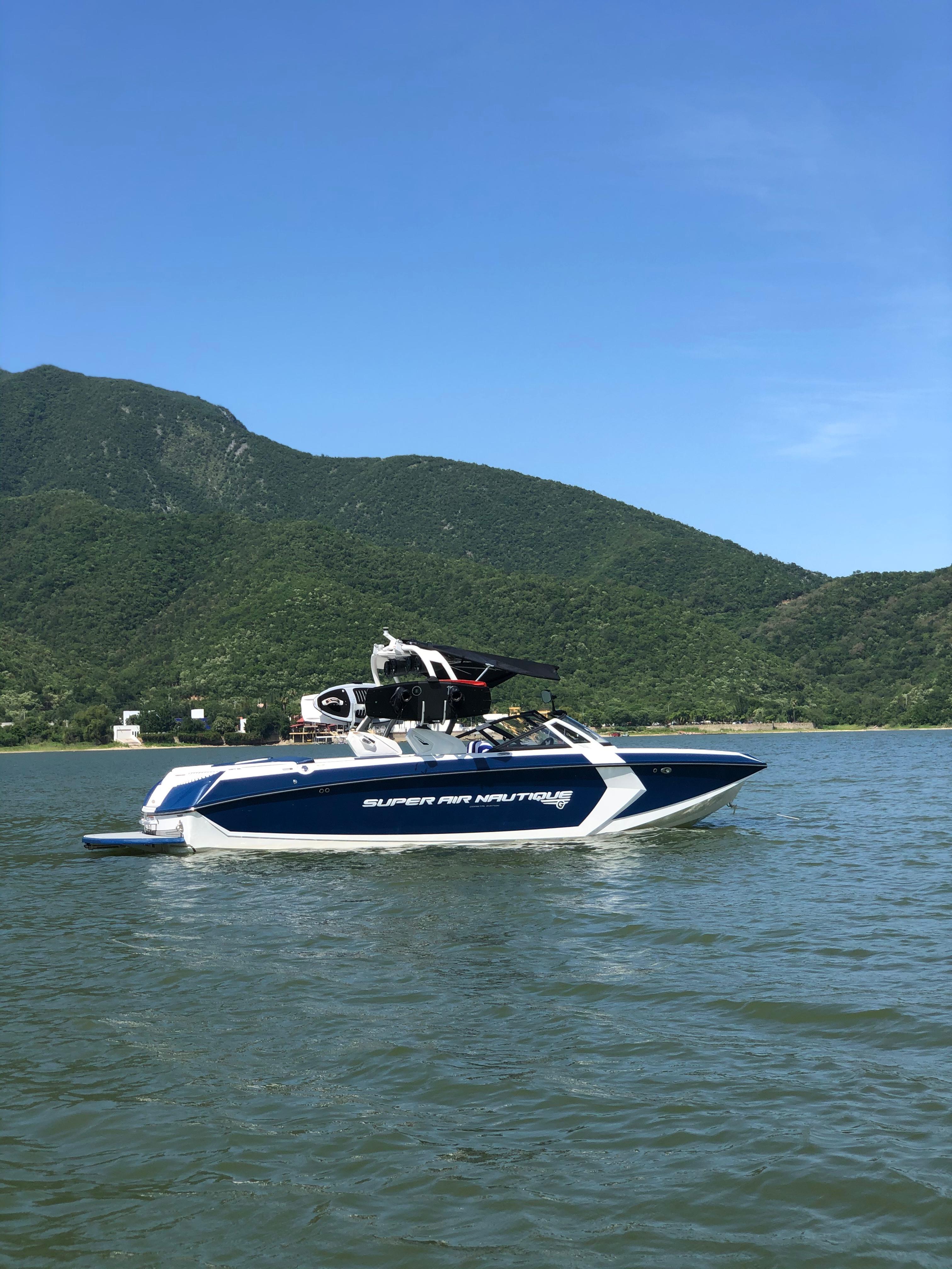 2017 Nautique Super Air Nautique G25 boat on a lake with mountain backdrop.