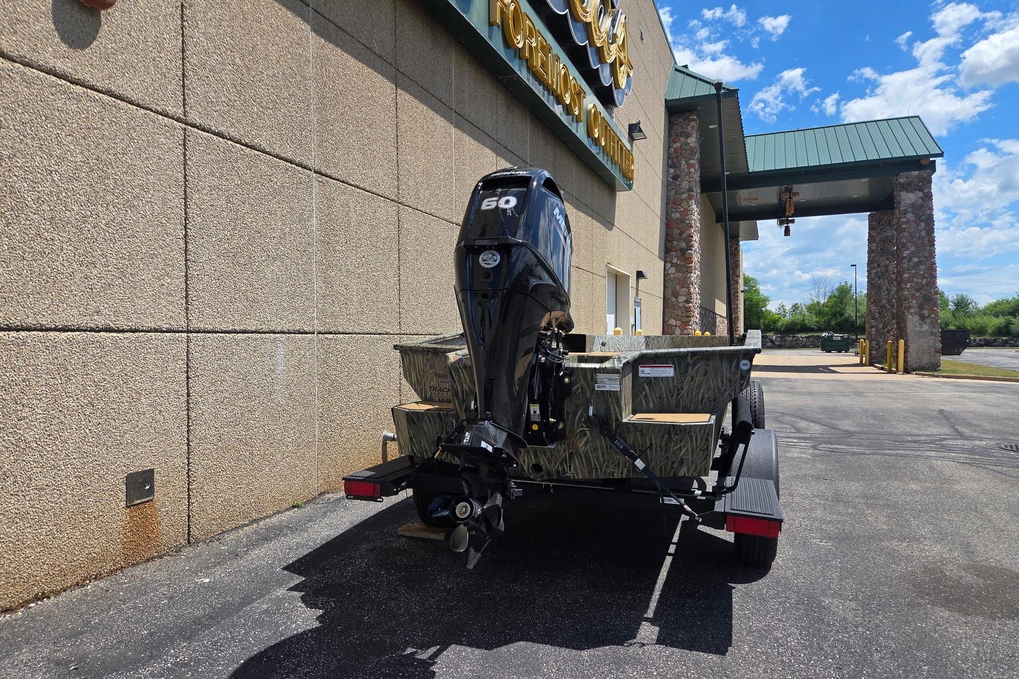 2026 Tracker Grizzly 1756 T Marsh boat with 60 HP motor parked outside a building.
