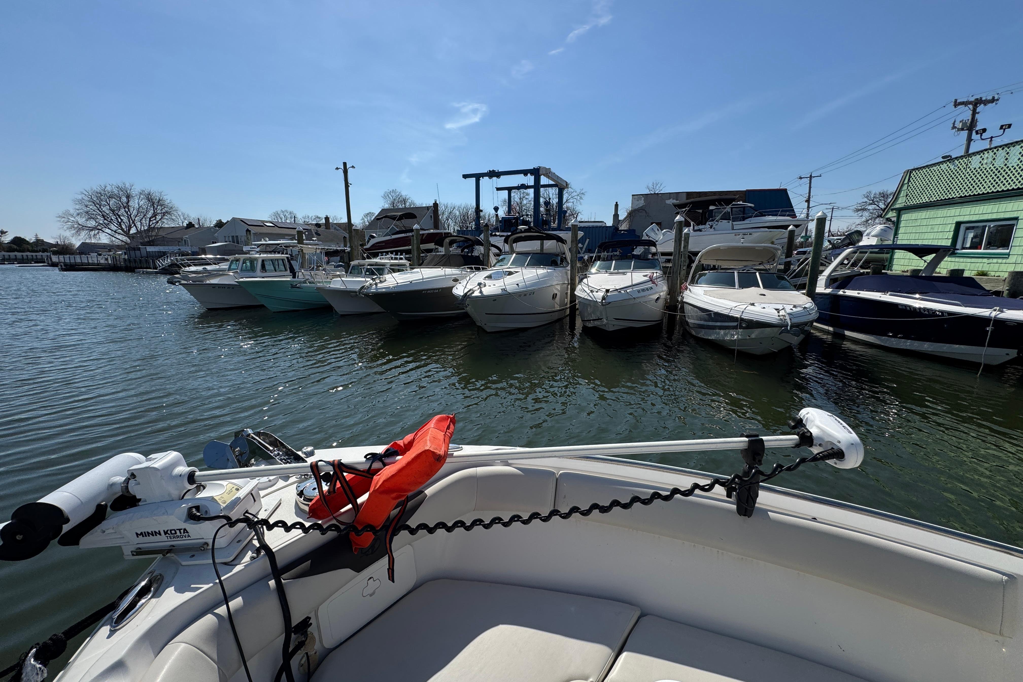 2022 Sailfish 242 CC boat docked with other boats in a marina under clear skies.