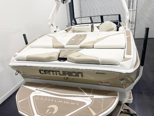 2025 Centurion NV213 boat with beige and white seating, rear view in a showroom.