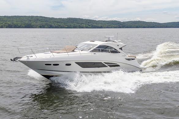 2016 Sea Ray Sundancer 510 cruising on a lake with lush green hills in the background.