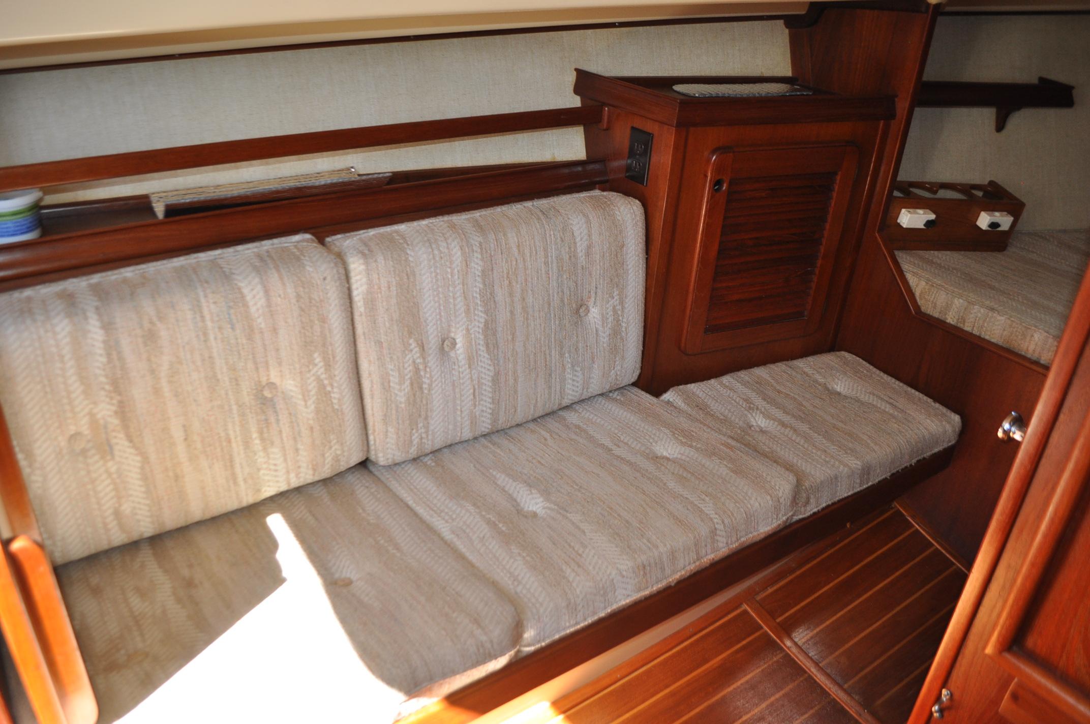 1989 Island Packet 27 interior with cushioned seating and wooden cabinetry.