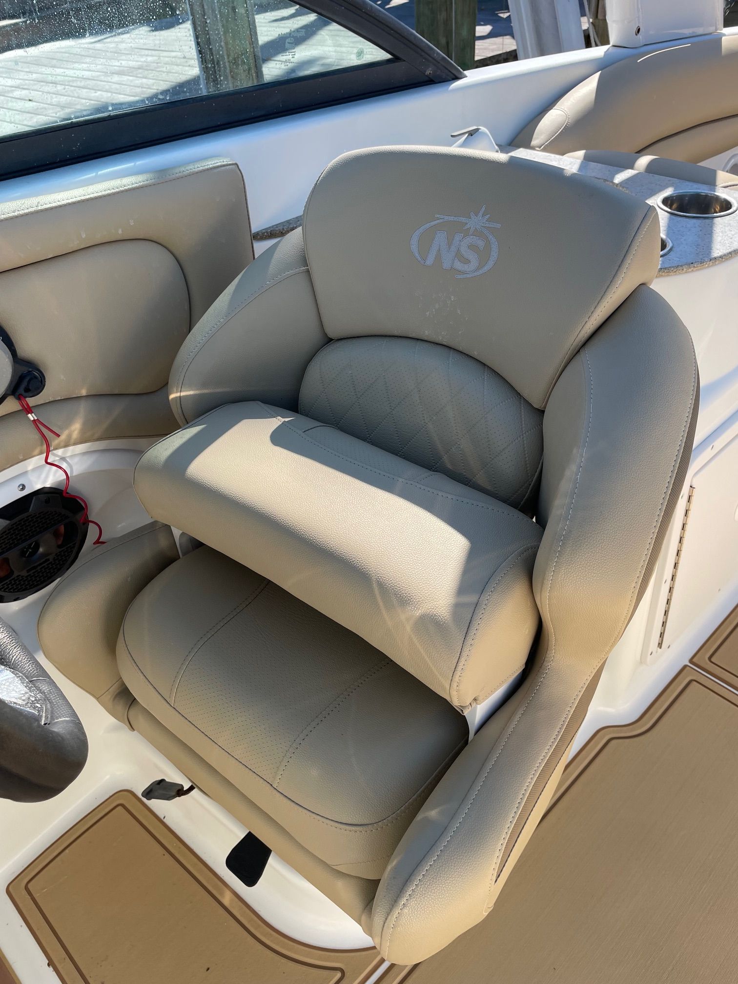 2019 NauticStar 243DC Sport Deck seat with beige upholstery and NS logo.