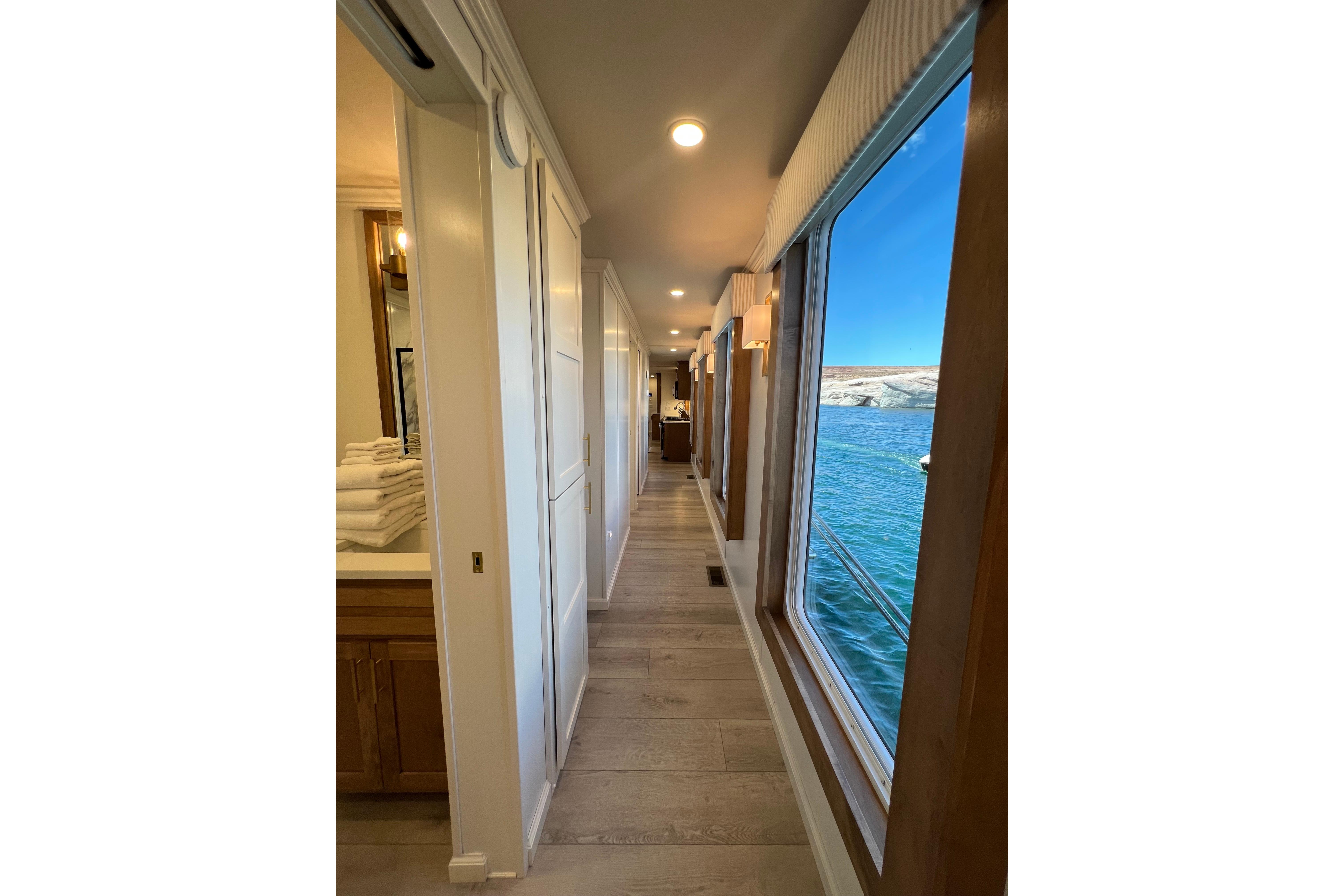 Hallway view inside 2025 Sumerset Excellence Multiple Shares houseboat, featuring large windows overlooking water.
