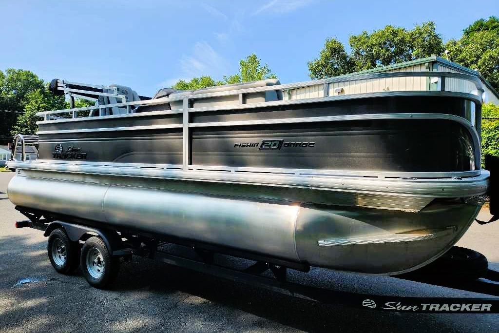2026 Sun Tracker Fishin' Barge 20 DLX pontoon boat on trailer, outdoors.