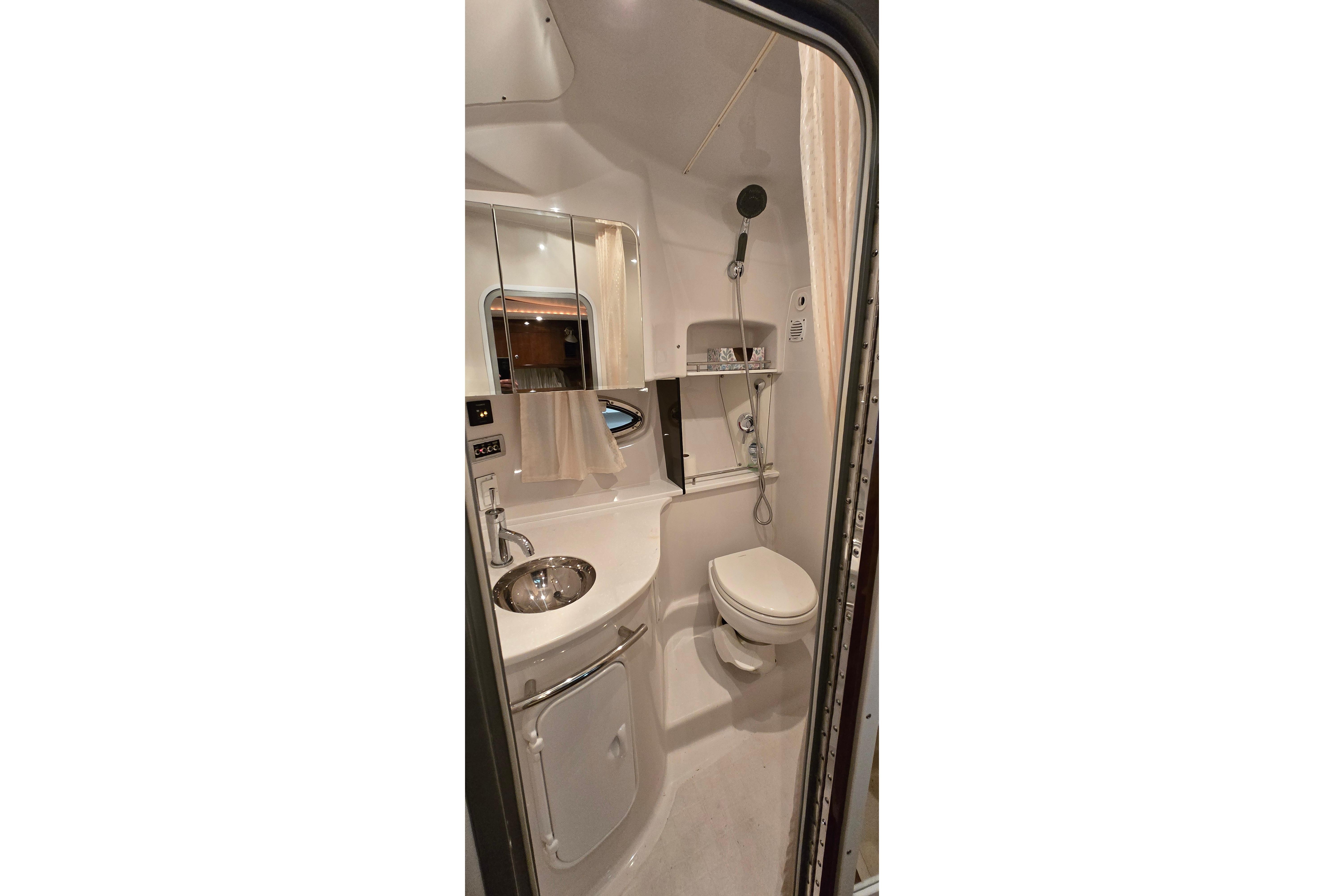Compact bathroom in 2018 Four Winns V355 boat, featuring sink, toilet, and shower.